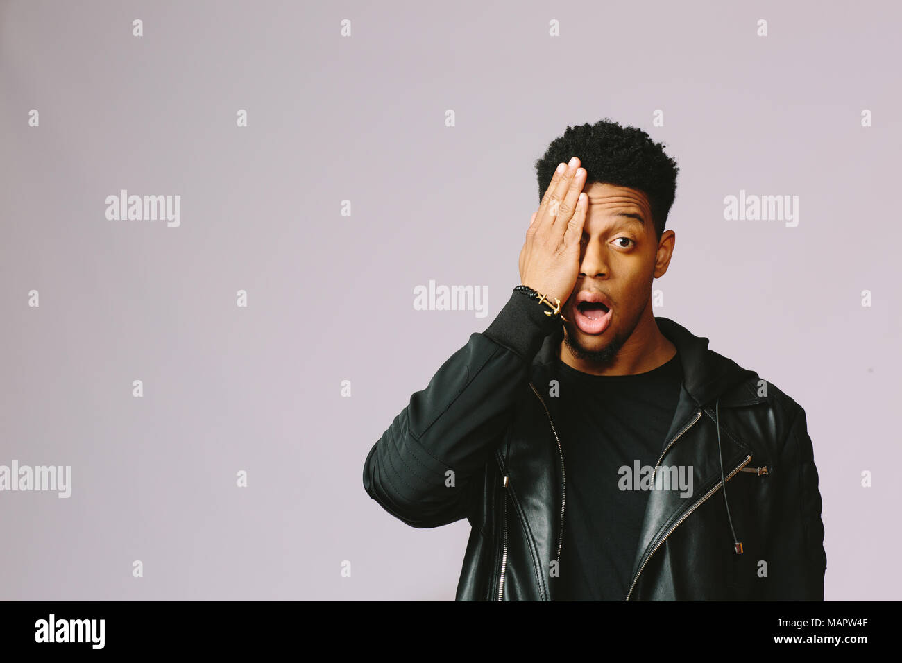 Portrait of a cool young man covering his eye with one hand, isolated ...
