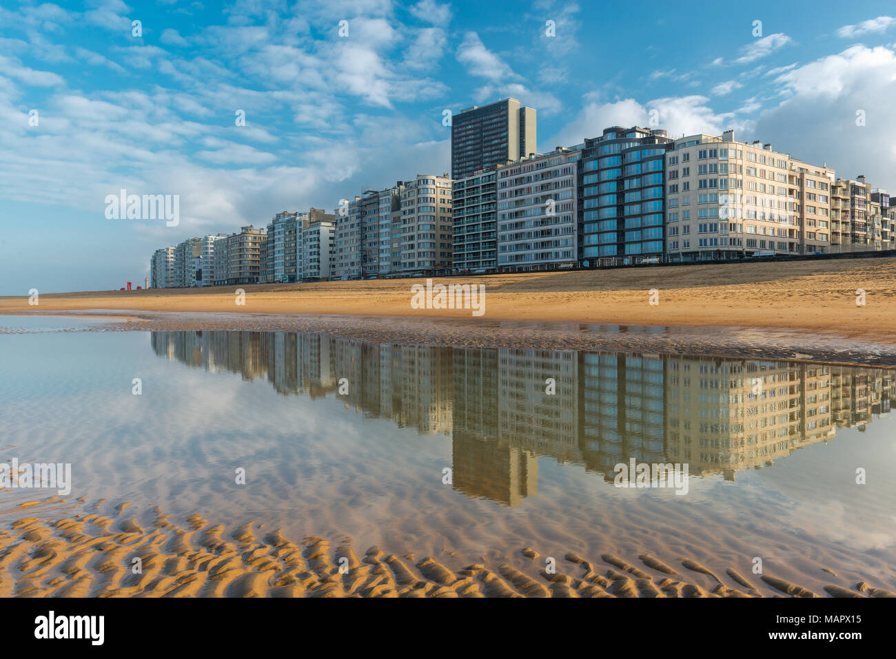 Reflection of the urban skyline of Ostend by its North Sea beach with a view over the waterfront promenade at sunset, West Flanders, Belgium. Stock Photo