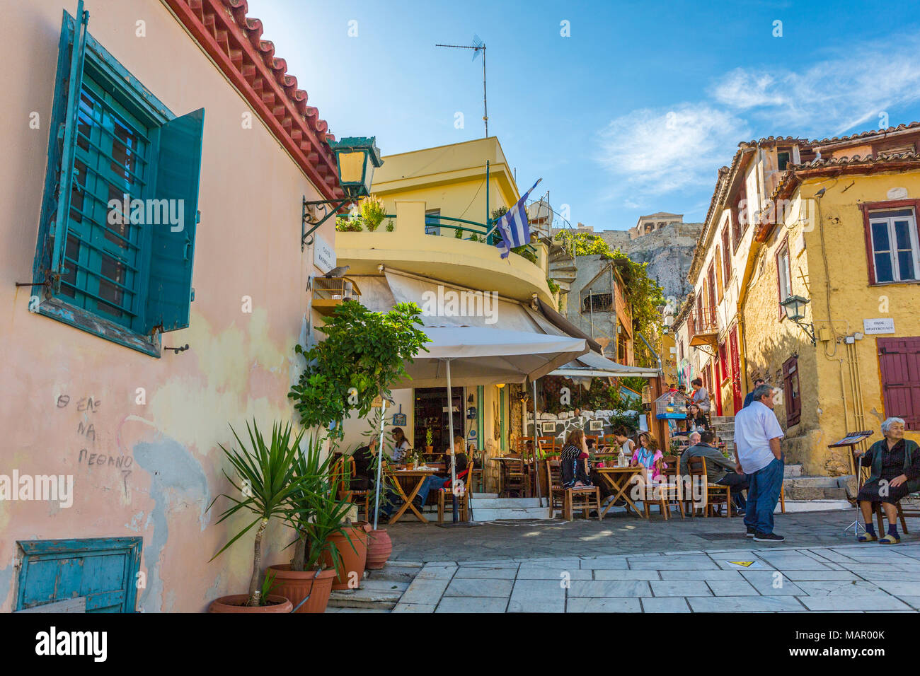 View of pastel coloured houses and cafe in Plaka District of Athens, overlooked by the Acropolis, Athens, Greece, Europe Stock Photo