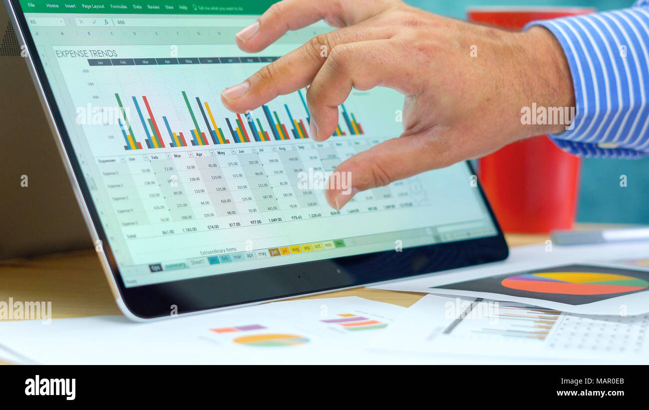 Businessman pointing and expanding graphs on modern touch screen ...