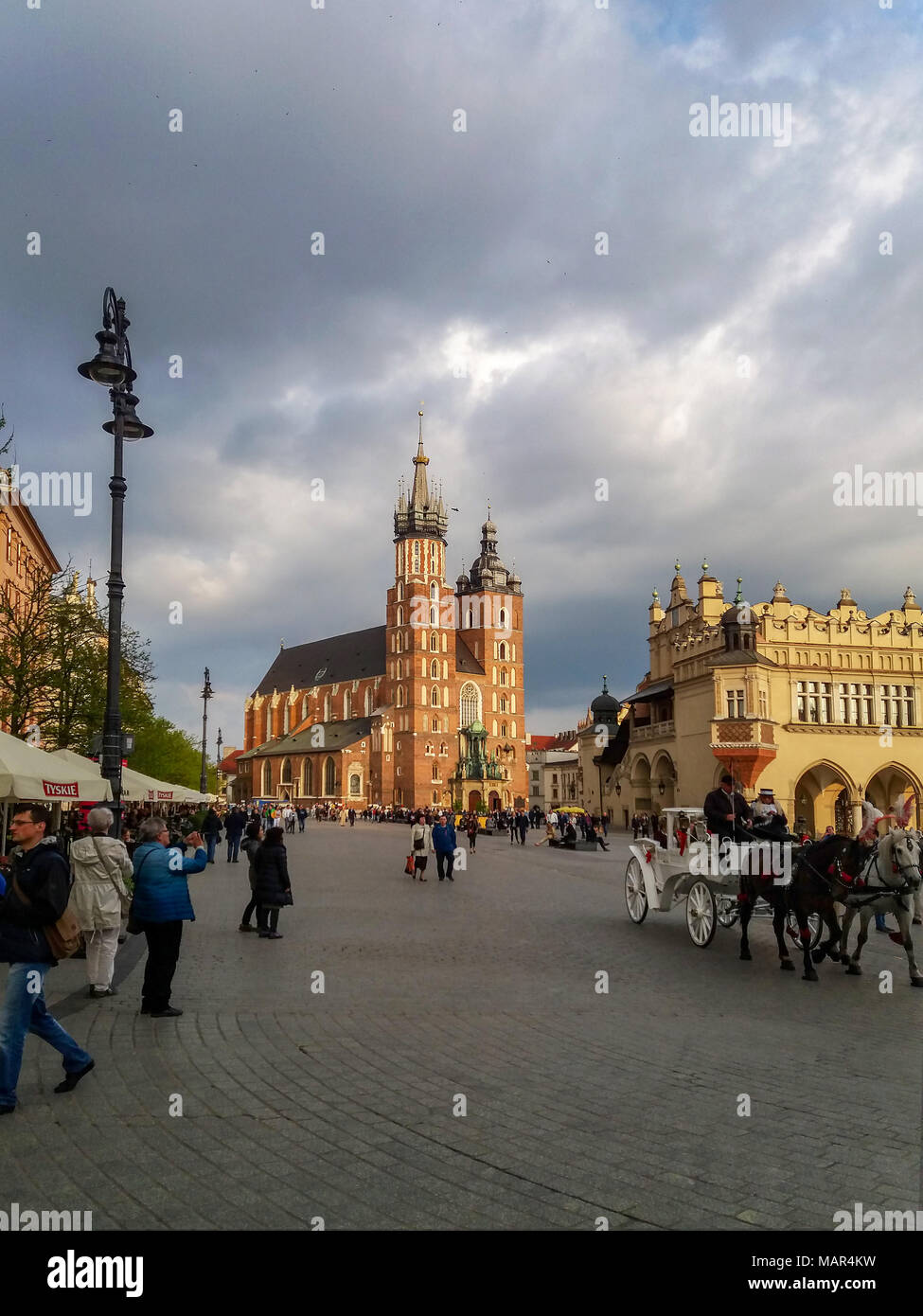 Krakow, Poland â€“ May 7, 2017: Main Market Square (Rynek), Gothic St Mary Church (Mariacki), old drapersâ€™ hall (Sukiennice), carriage  and walking  Stock Photo