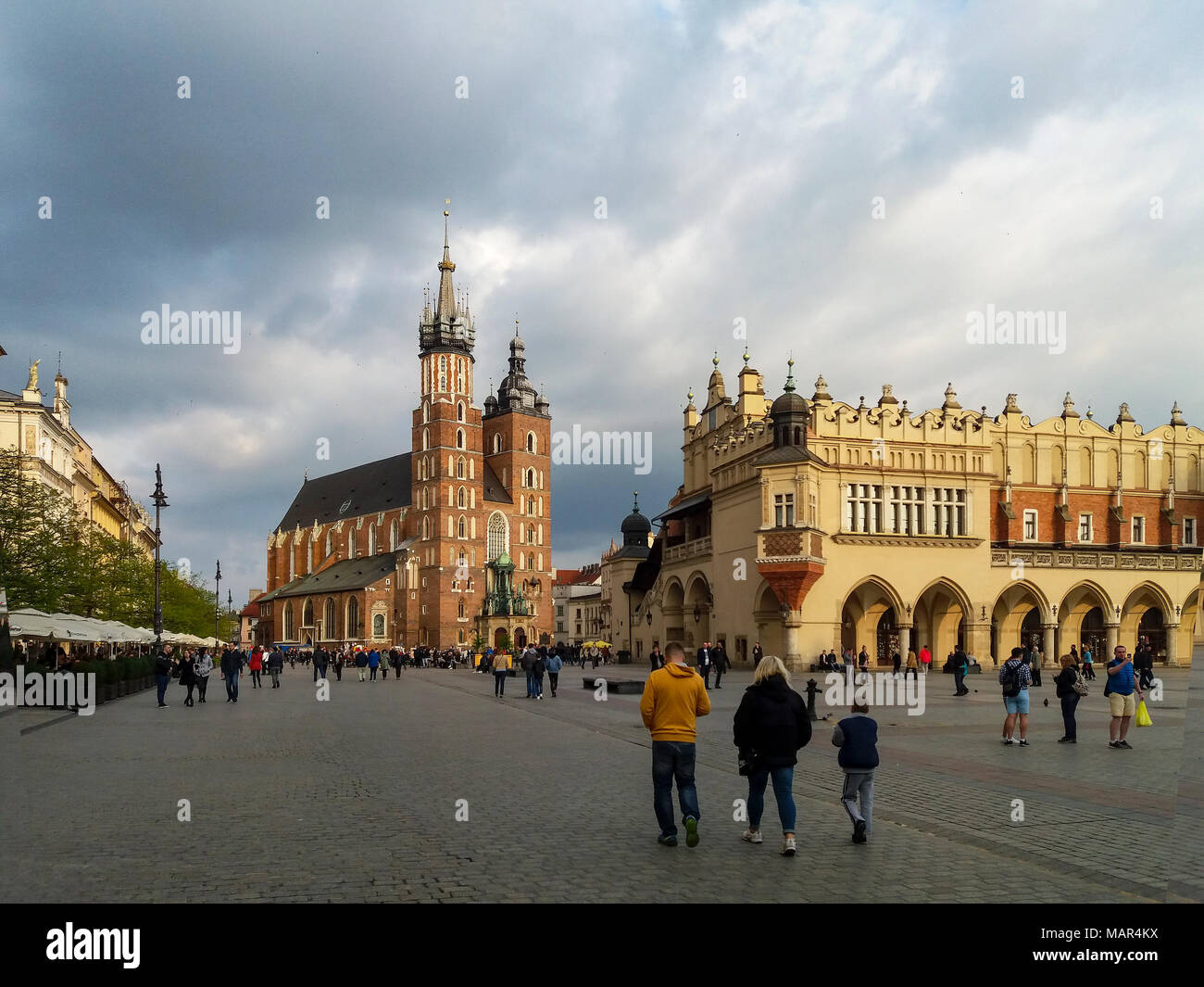Krakow, Poland – May 7, 2017: Main Market Square (Rynek), Gothic St Mary Church (Mariacki), old drapers’ hall (Sukiennice) and walking people. Weather Stock Photo