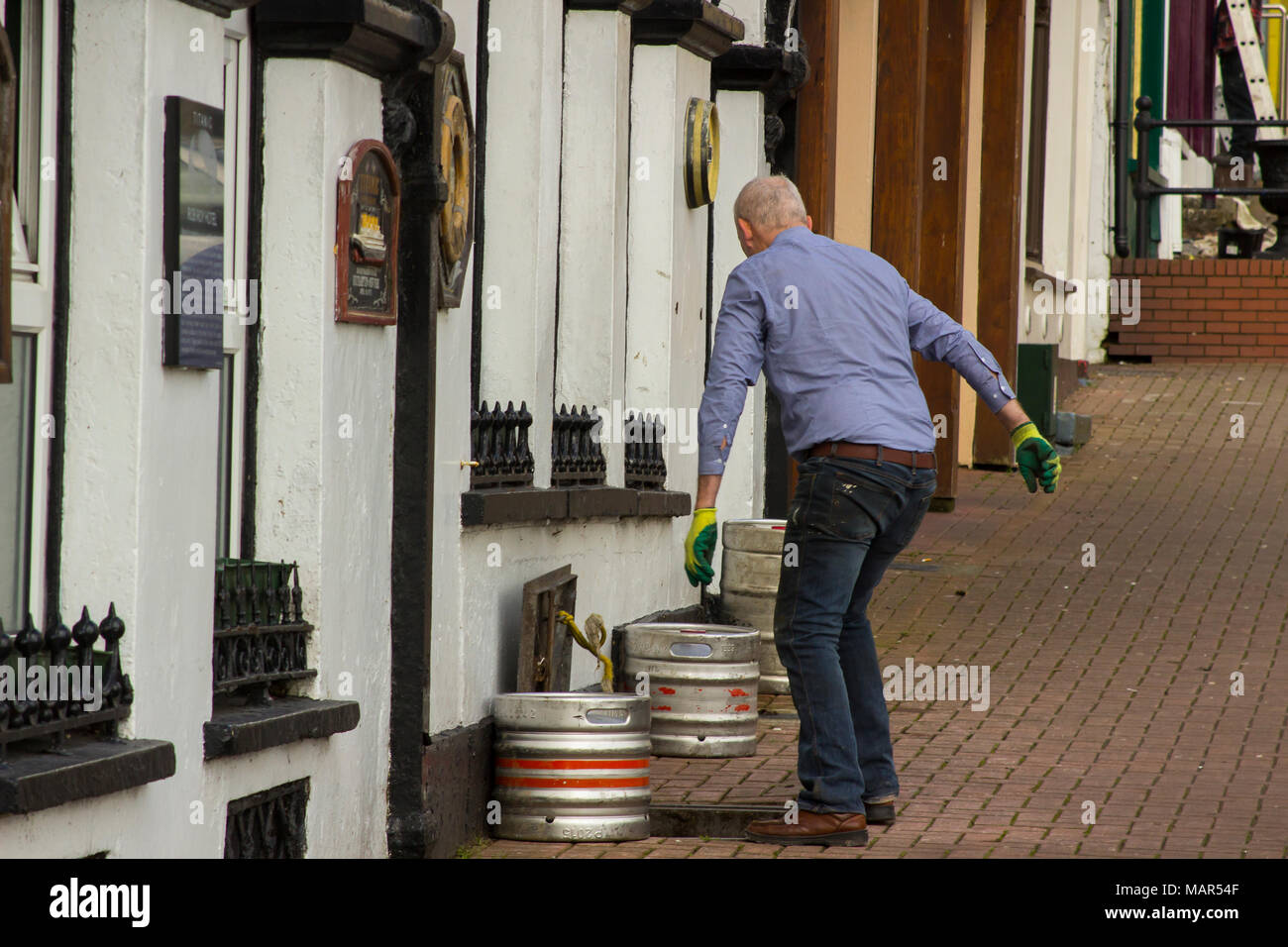 16 March 2018 Cobh County Cork Ireland A pub landlord dropping aluminium barrels of beer into a traditional cellar for storage Stock Photo