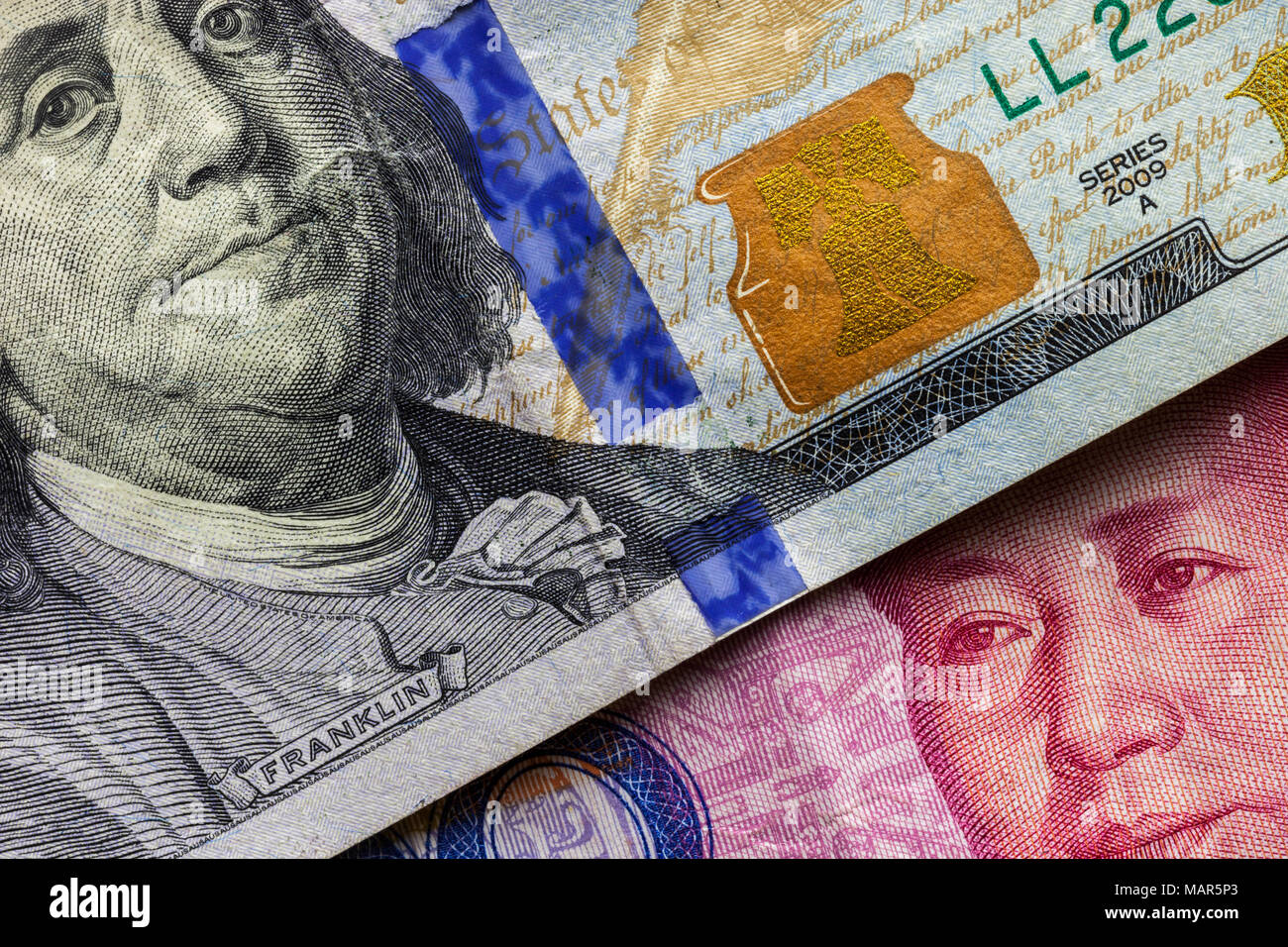 Close up of one hundred Dollar banknote over a 100 Yuan banknote with focus on portraits of Benjamin Franklin and Mao Tse-tung/USA vs China trade war  Stock Photo
