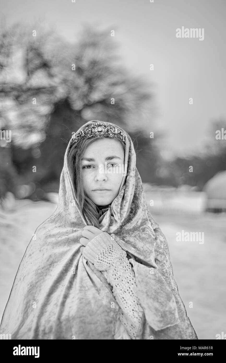woman in snowy landscape wearing a tiara and cloak Stock Photo