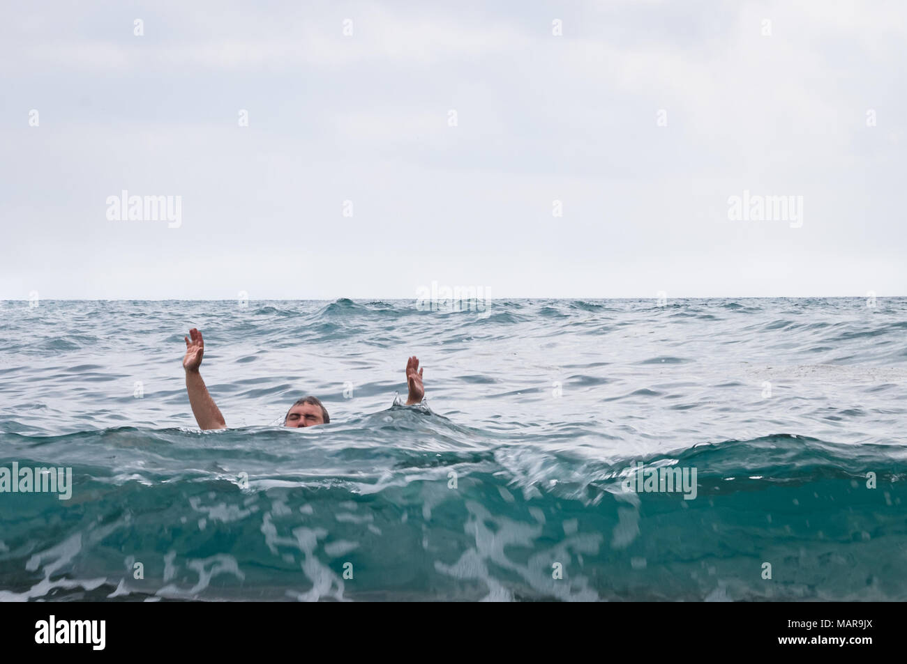 Man drowns and asks for help raising his hands up Stock Photo