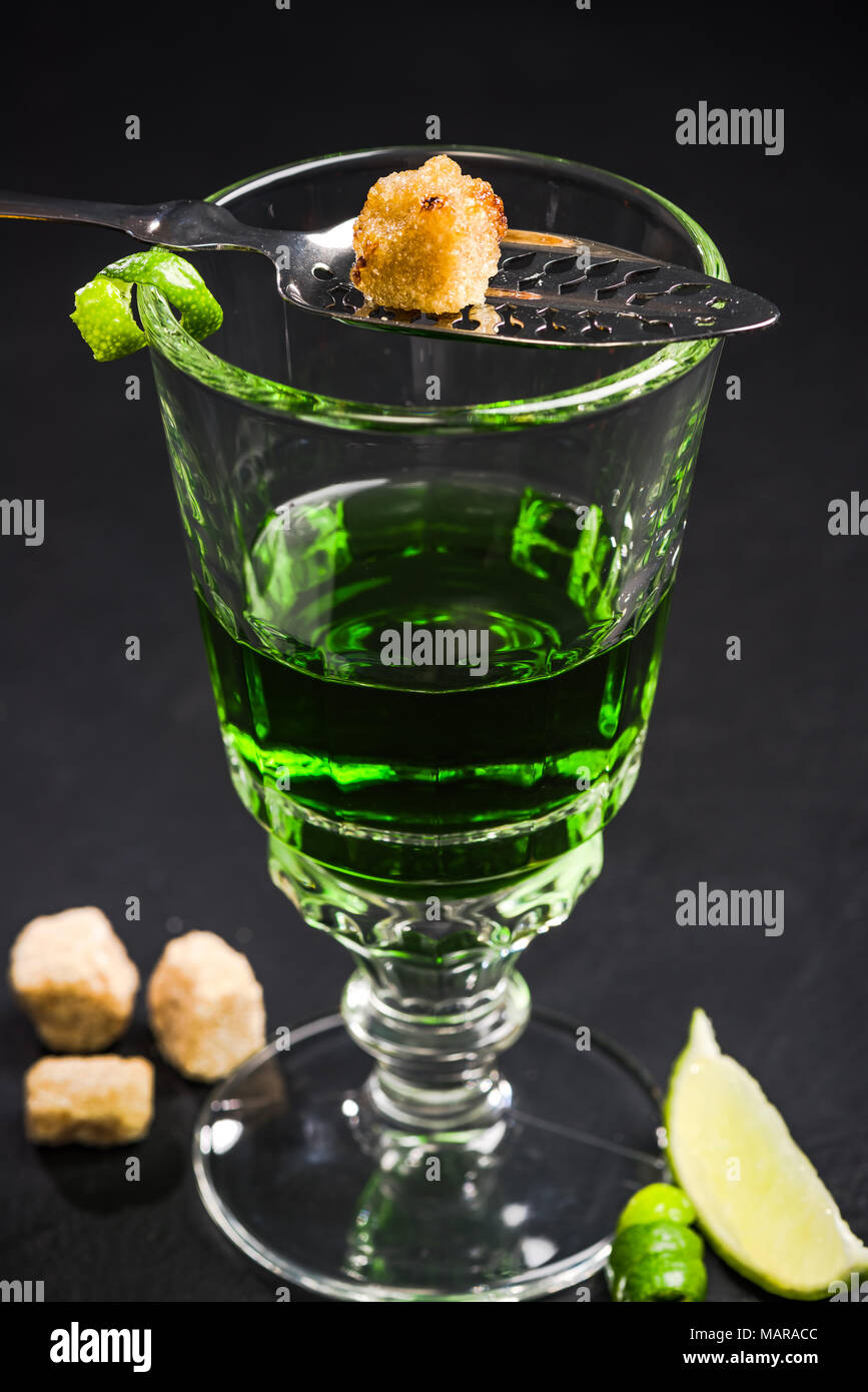 Carmelized sugar cube over green Absinthe vodka Stock Photo Alamy