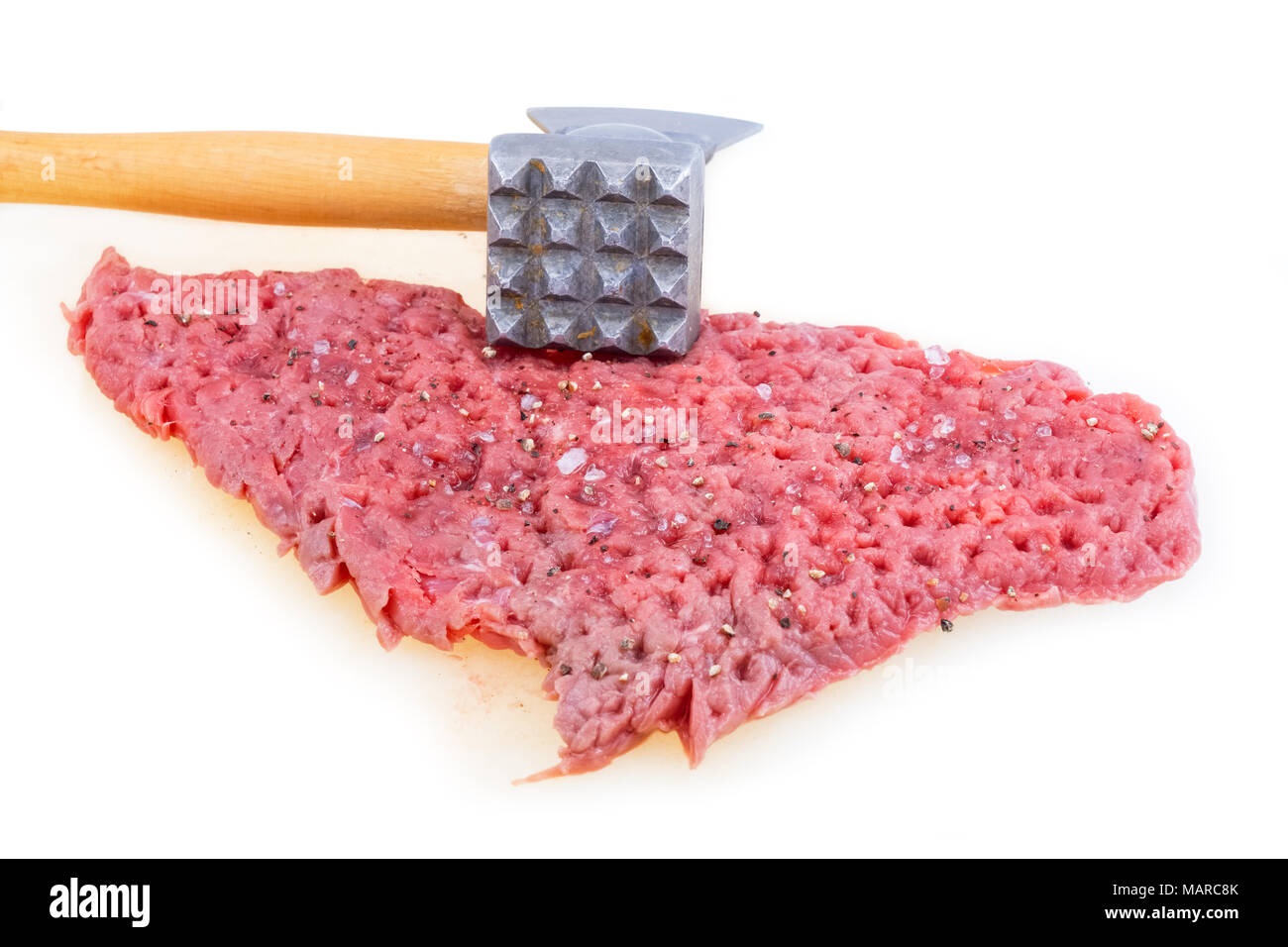 Hands tenderizing meat with kitchen hammer on a white board Stock Photo