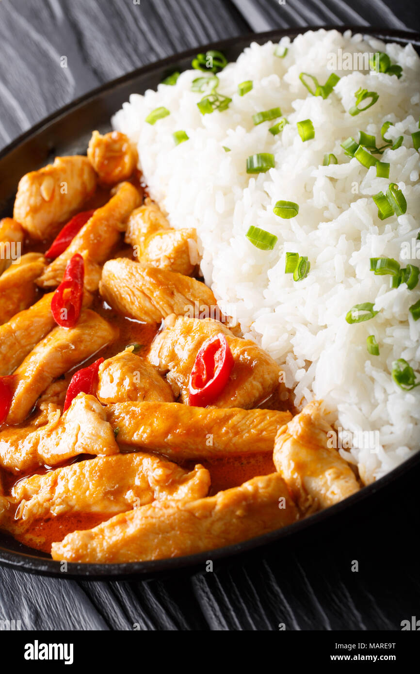 Thai chicken panang curry with rice and green onion close-up on a plate. vertical Stock Photo