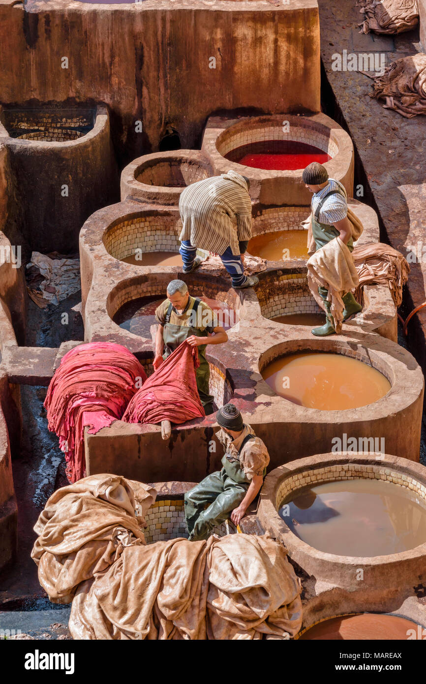 MOROCCO FES MEDINA SOUK CHOUWARA TANNERIES CIRCULAR VATS WITH COLOURED DYES AND HIDES WITH FOUR WORKERS SORTING SKINS Stock Photo