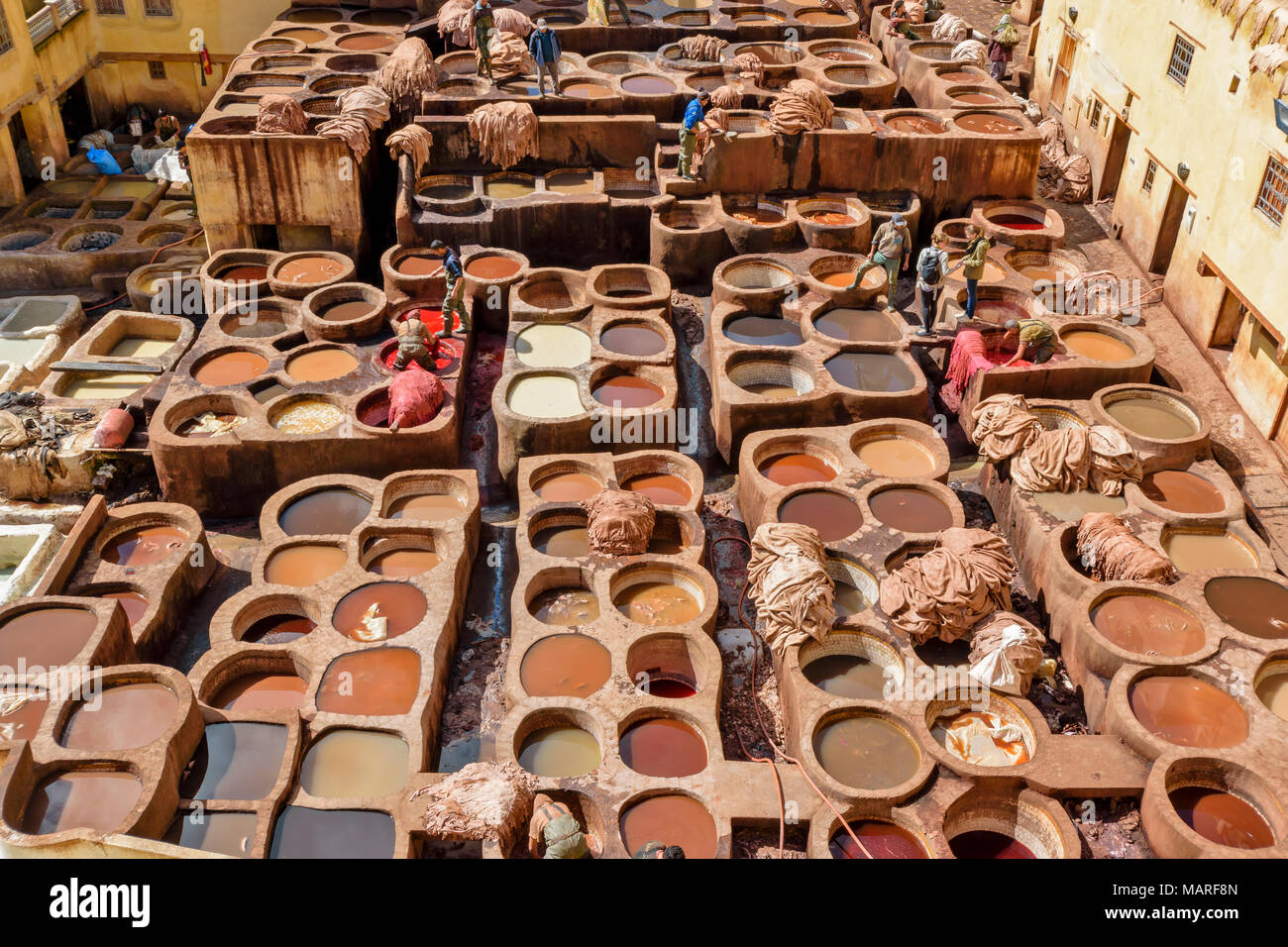MOROCCO FES MEDINA SOUK CHOUWARA TANNERY TANNERIES VIEW OF THE WORKERS AND CIRCULAR VATS OR TANKS WITH VARIOUS MULTICOLOURED DYES CONTAINING THE HIDES Stock Photo