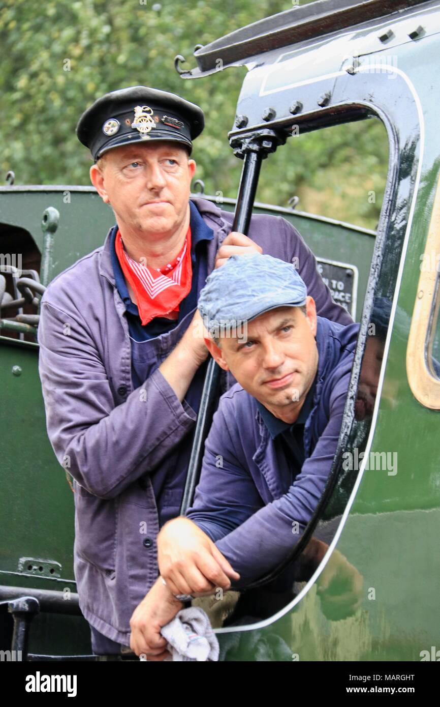 A portrait of the driver and his fireman looking down the side of Repton, a green steam engine on the North York Moors Railway. Stock Photo