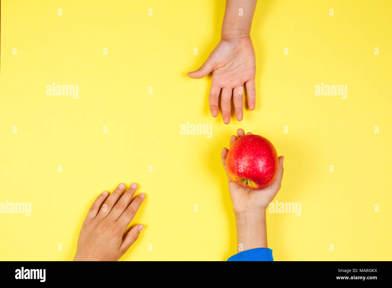 Kid hand taking red apple from another child's hands Stock Photo
