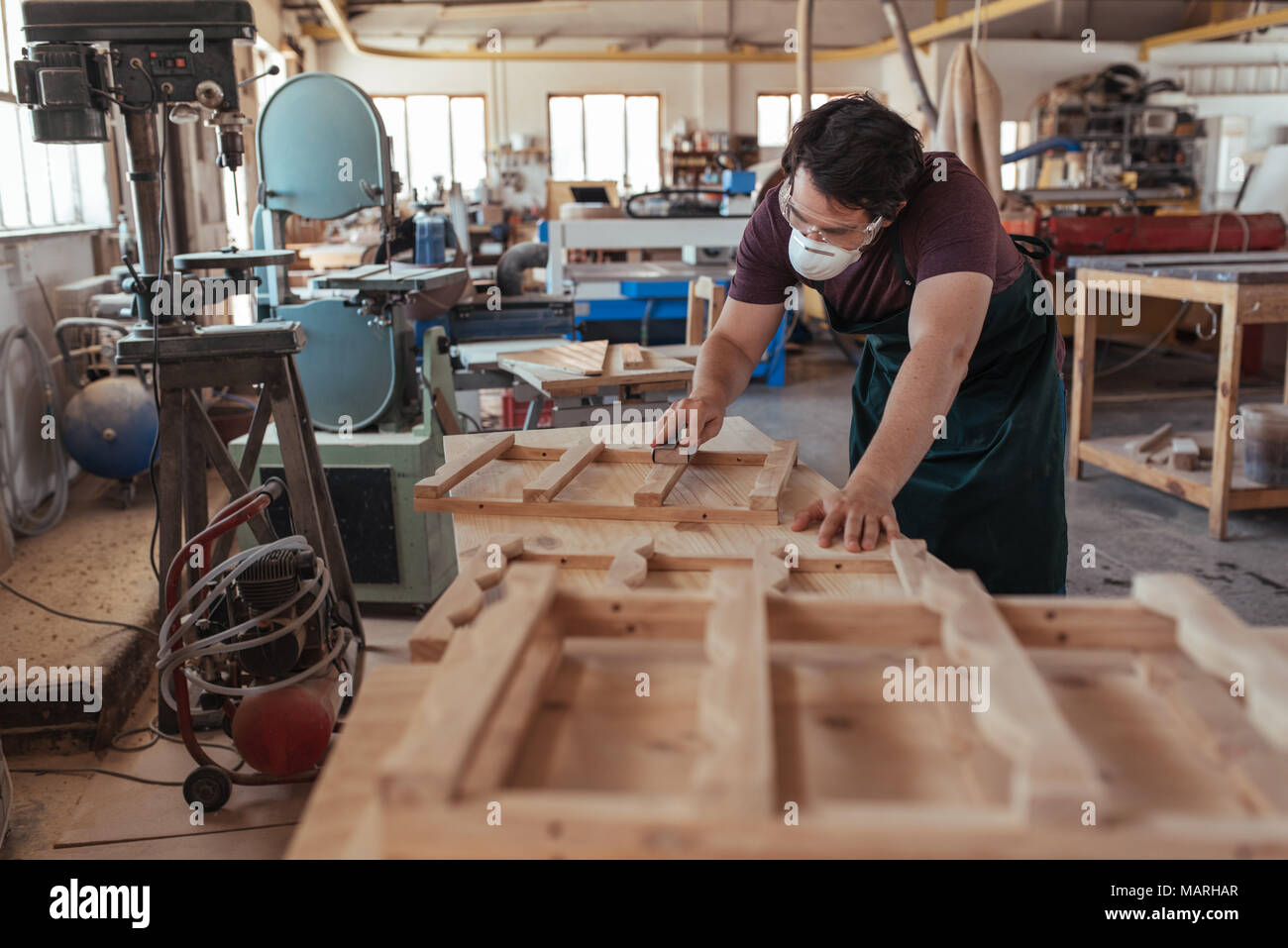 Skilled woodworker sanding furniture in his large workshop Stock Photo