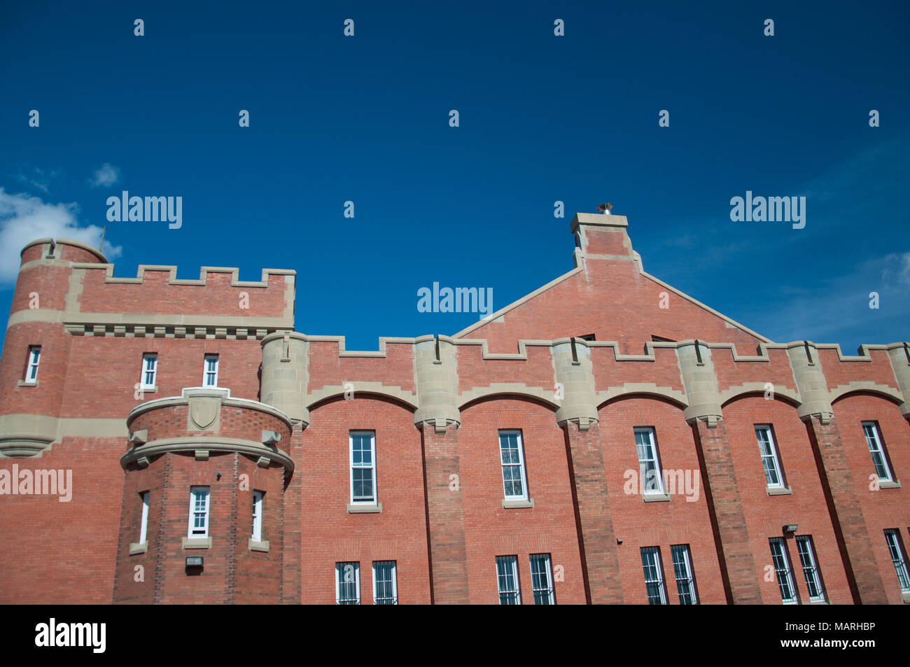 Red brick facade of the fotress inspired Mewata Armoury in downtown Calgary, Alberta. The Armouy has square corner towers, buttresses with turrets and Stock Photo