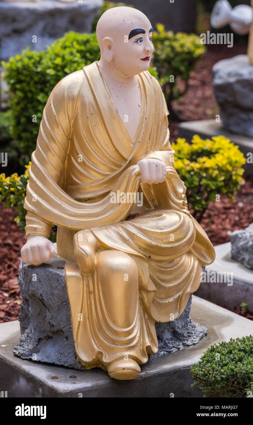 Hacienda Heights, CA, USA - March 23, 2018:  Closeup of golden draped Angaja with sack in Arhat garden  at Hsi Lai Buddhist Temple. Green and gray sur Stock Photo