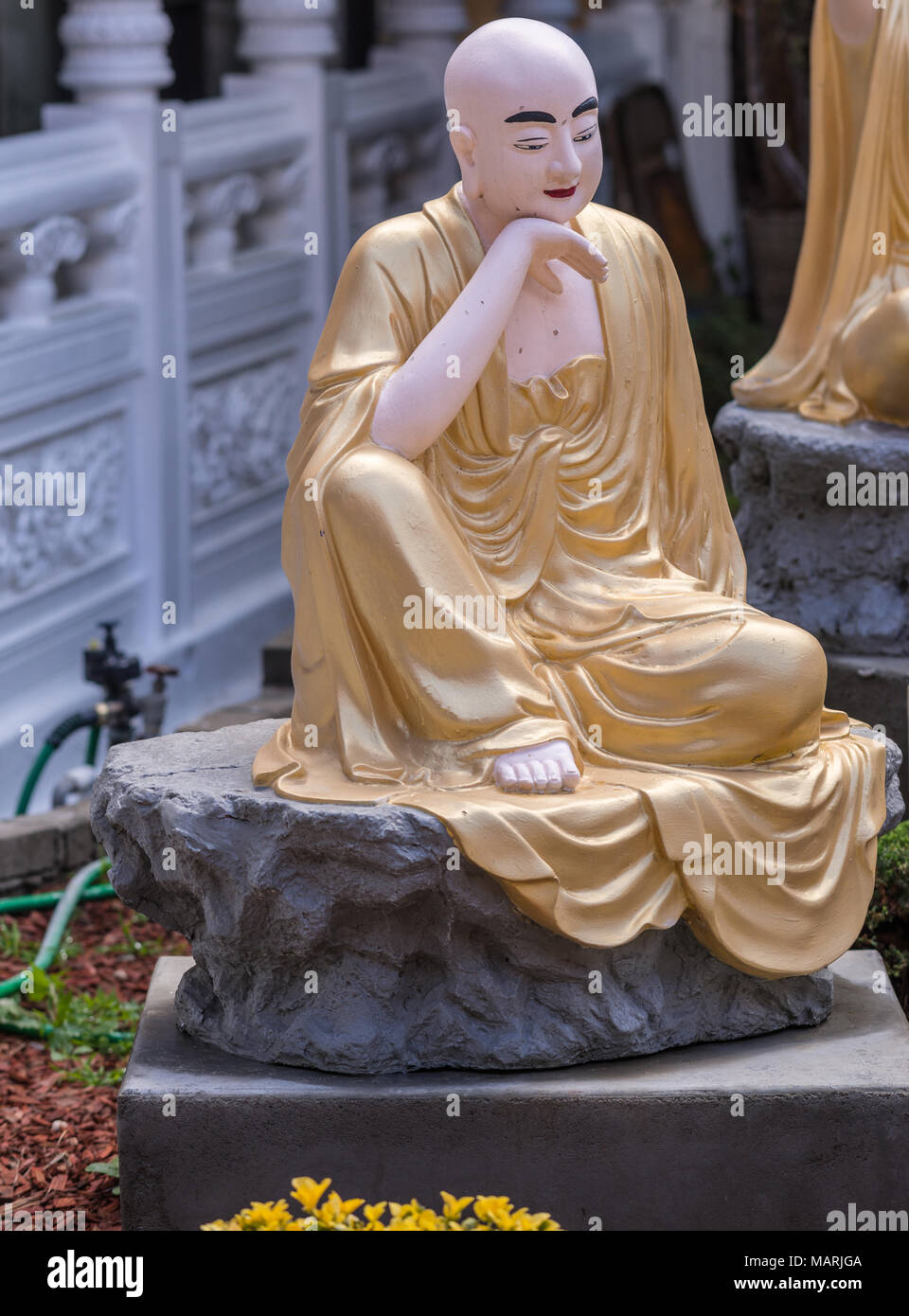 Hacienda Heights, CA, USA - March 23, 2018:  Closeup of golden draped Rahula with sack in Arhat garden at Hsi Lai Buddhist Temple. White and gray surr Stock Photo