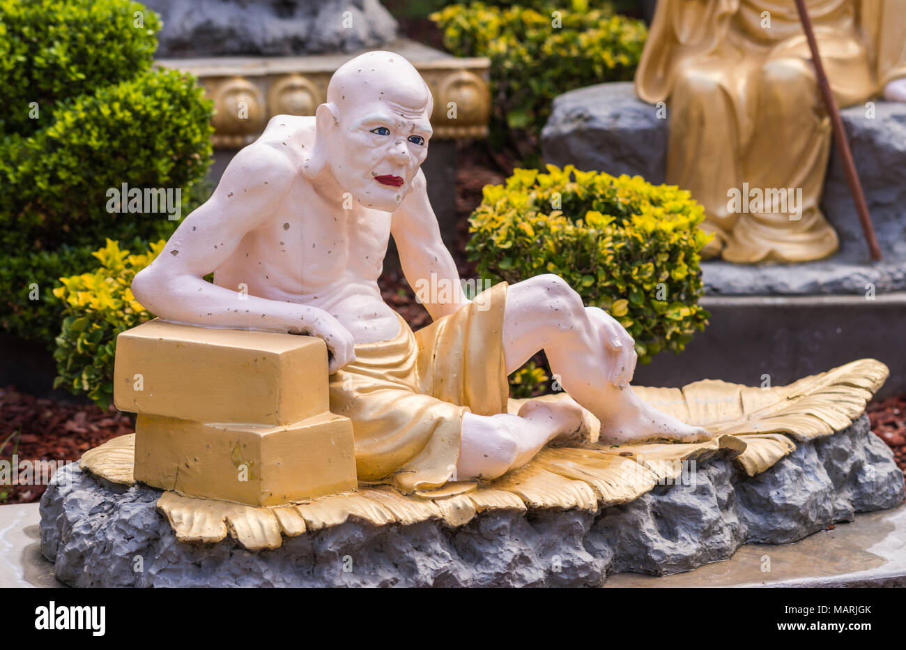 Hacienda Heights, CA, USA - March 23, 2018:  Closeup of golden draped Vanavasin in Arhat garden at Hsi Lai Buddhist Temple. White and gray surrounding Stock Photo