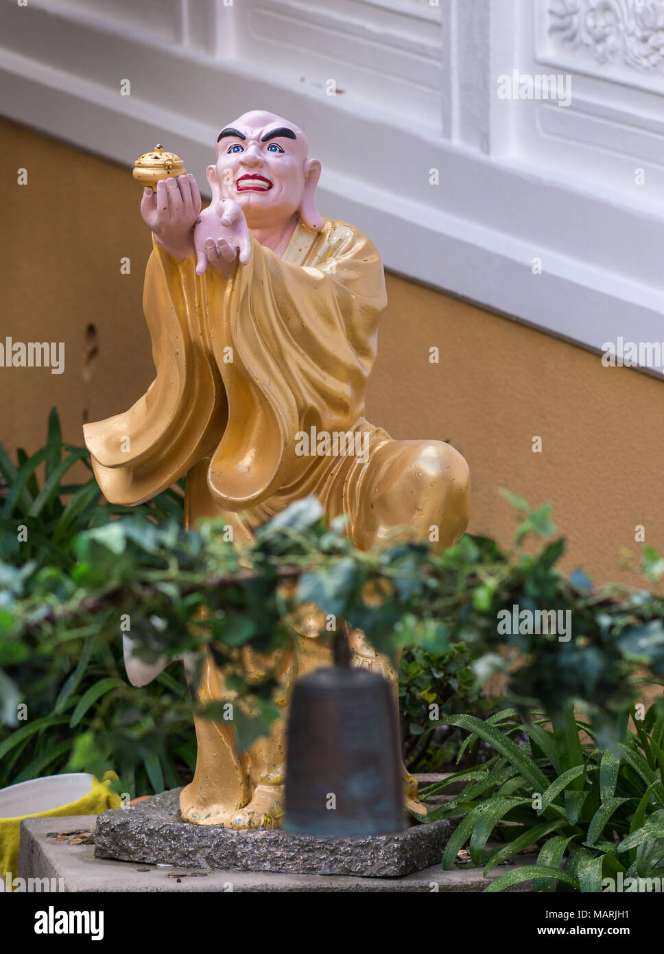 Hacienda Heights, CA, USA - March 23, 2018:  Closeup of golden draped Kanakabharadvaja with bown in Arhat garden at Hsi Lai Buddhist Temple.  Green pl Stock Photo
