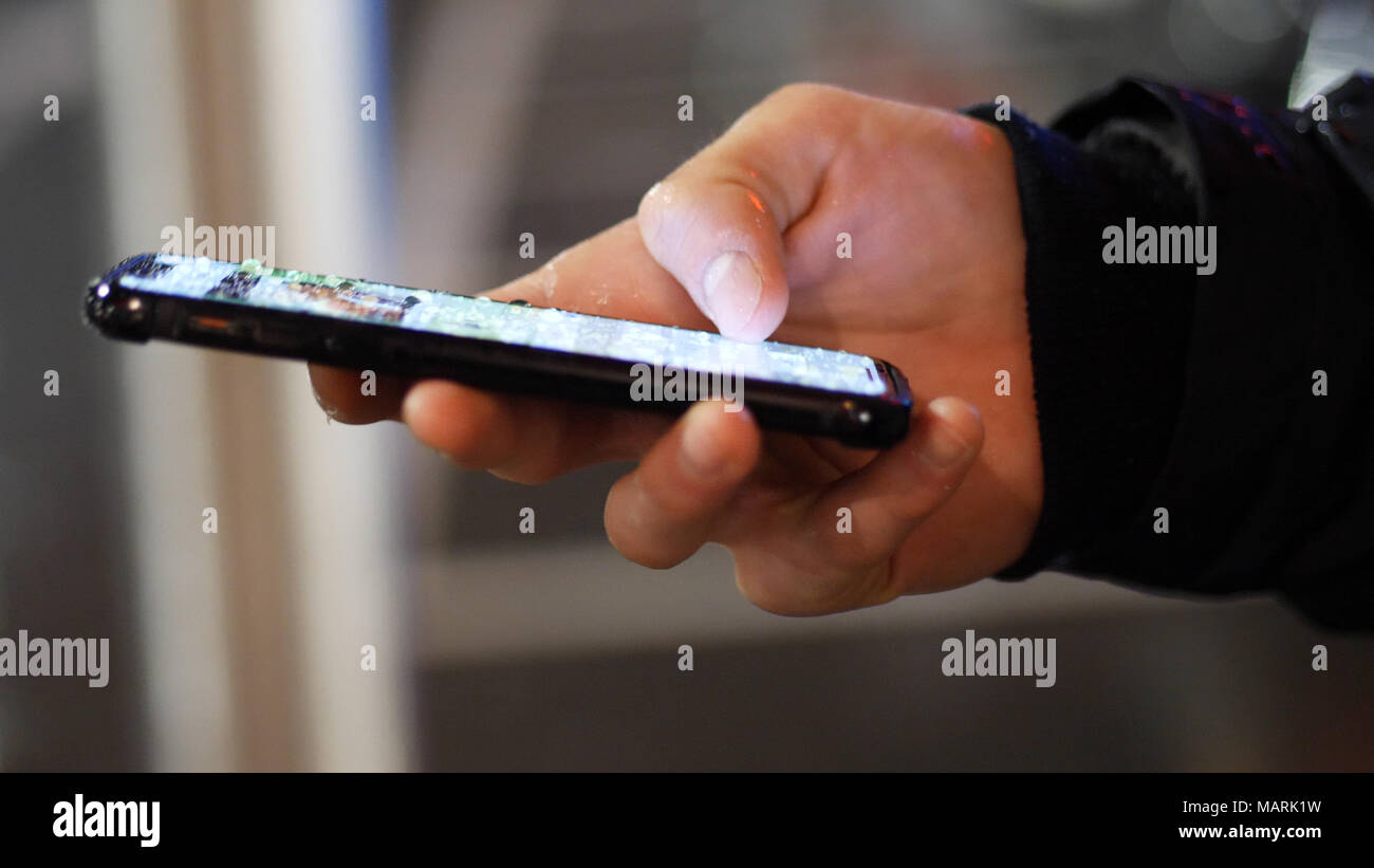 Male hands typing and using water-proof smartphone under rain dripping on the display Stock Photo