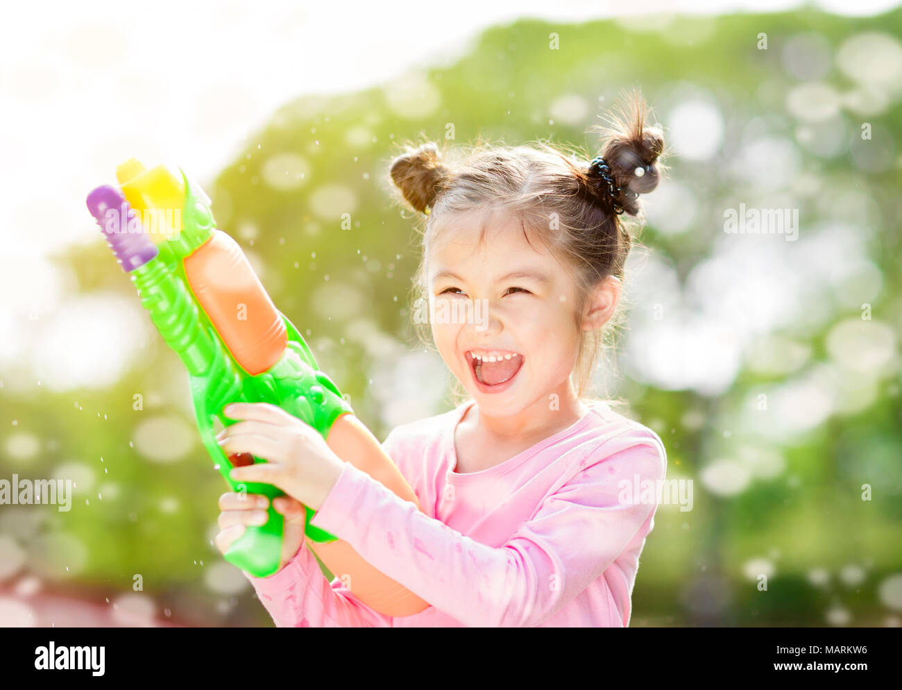 happy little girl playing water guns Stock Photo