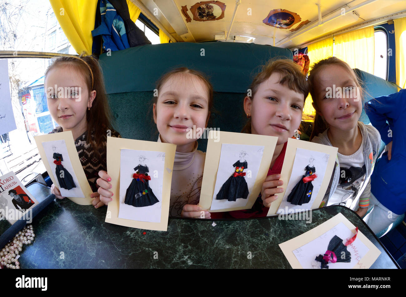 Teen girls sitting in the streetcar cabin and showing their handmade work - applique papers.March 26, 2018. Kiev, Ukraine Stock Photo