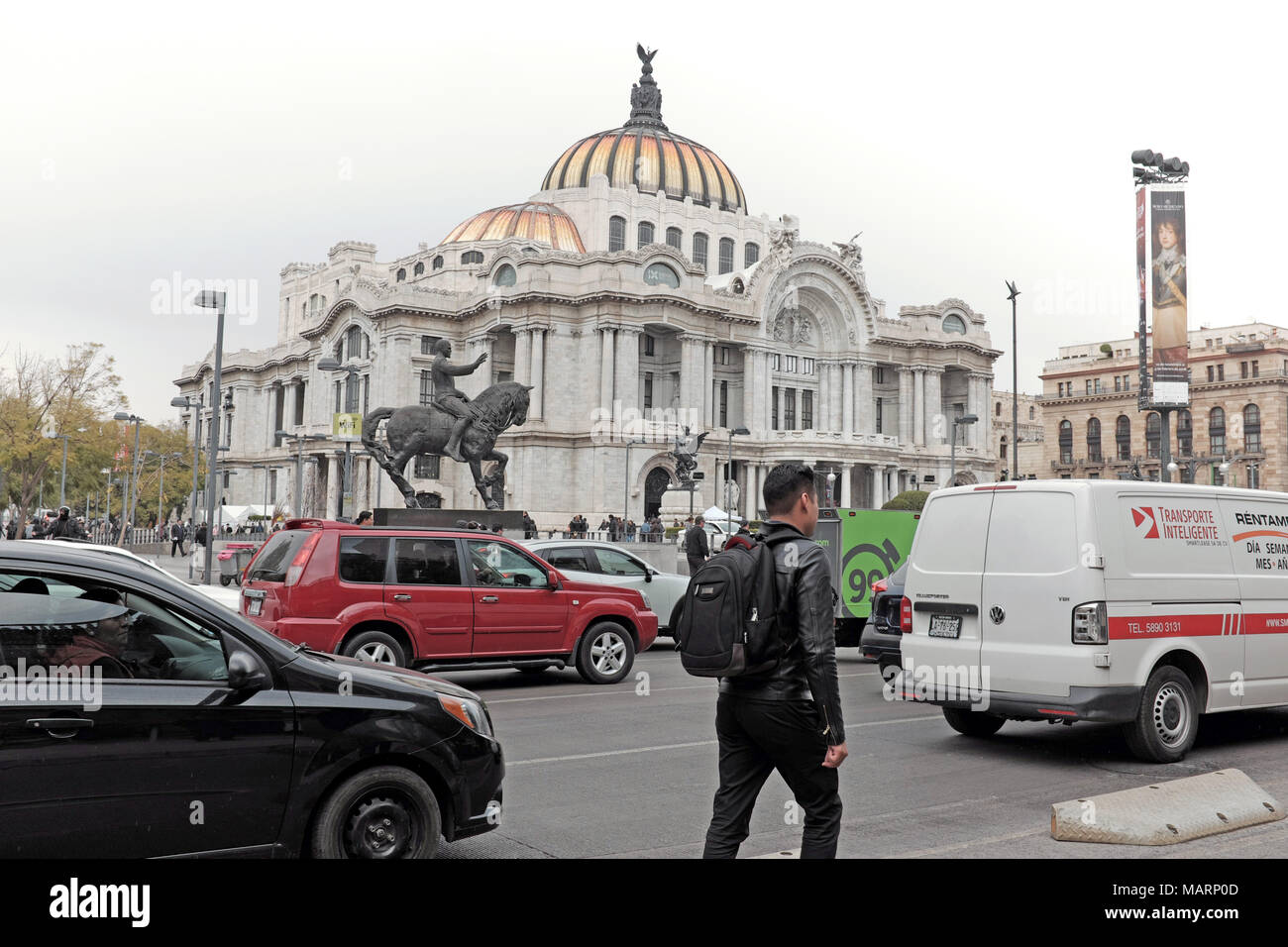 A man walks with traffic in the historic center of Mexico City, Mexico, passing by the palatial Palacio de Bellas Artes. Stock Photo