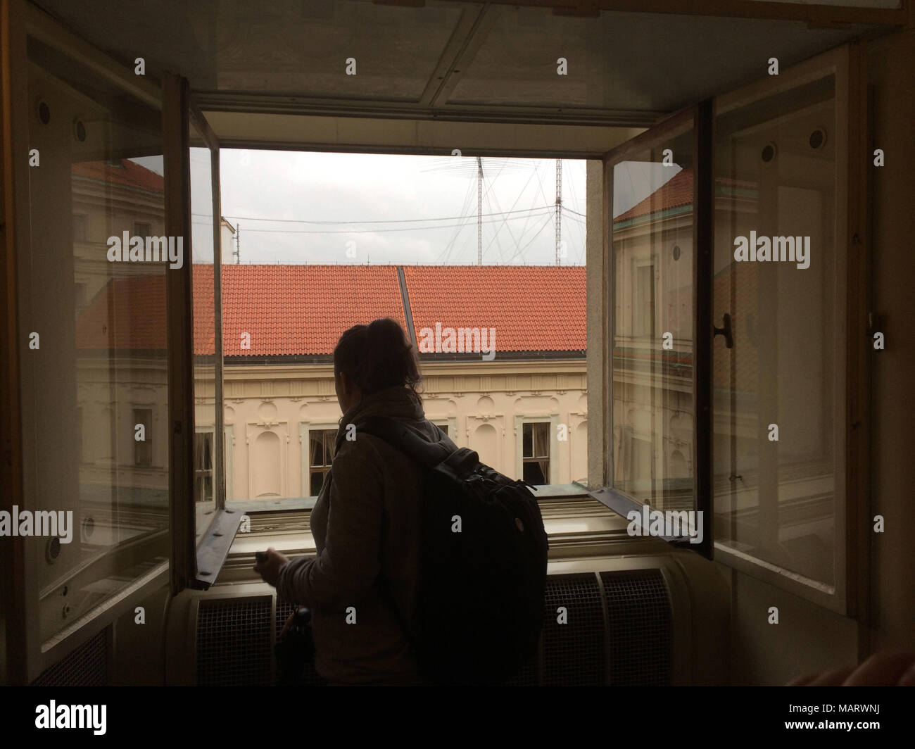 Visitor looks out from the bathroom window in the official residence of the Foreign Minister of Czechoslovakia Jan Masaryk in the Czernin Palace (Černínský palác) in Hradčany district in Prague, Czech Republic. On 10 March 1948, Jan Masaryk was found dead under the window of the bathroom. He probably committed suicide by jumping out of the window or was murdered by the Communist authorities. Stock Photo