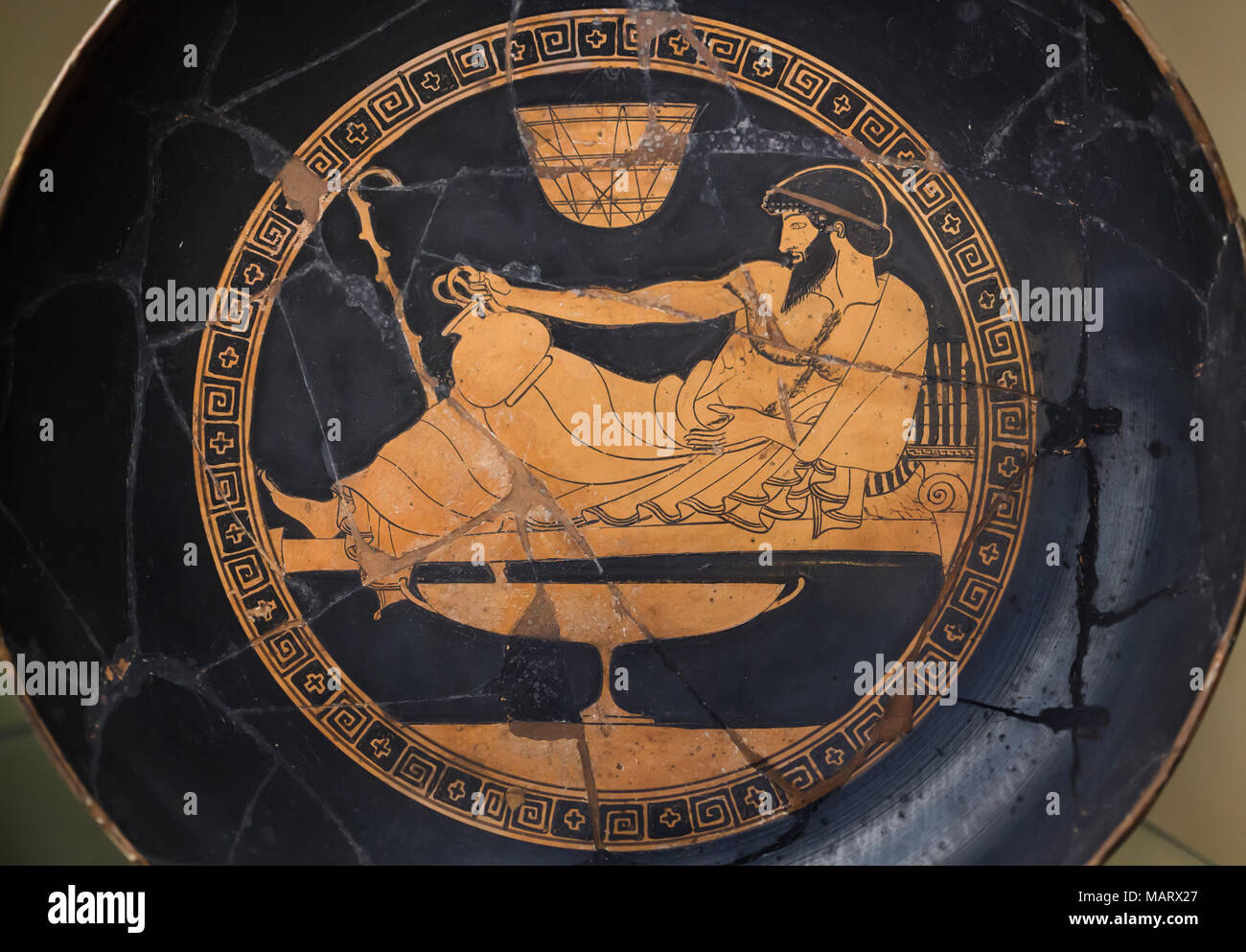 Bearded man reclining on the kline. Attic red-figure kylix painted by Douris Painter dated from the end of the 6th century BC or the beginning of the 5th century BC on display in the Museo archeologico nazionale (National Archaeological Museum) in Florence, Tuscany, Italy. Stock Photo