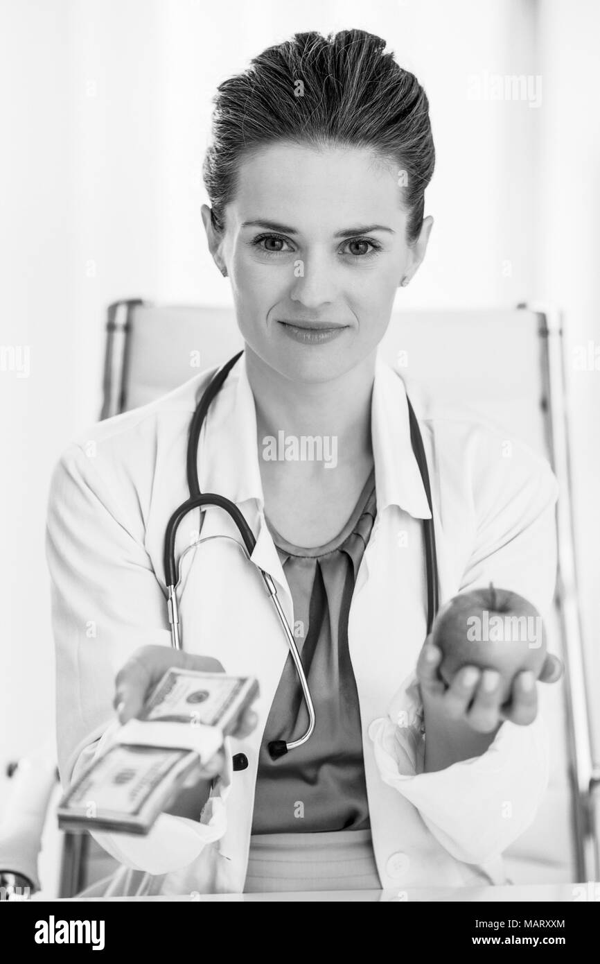 Doctor woman showing apple and pack of money Stock Photo