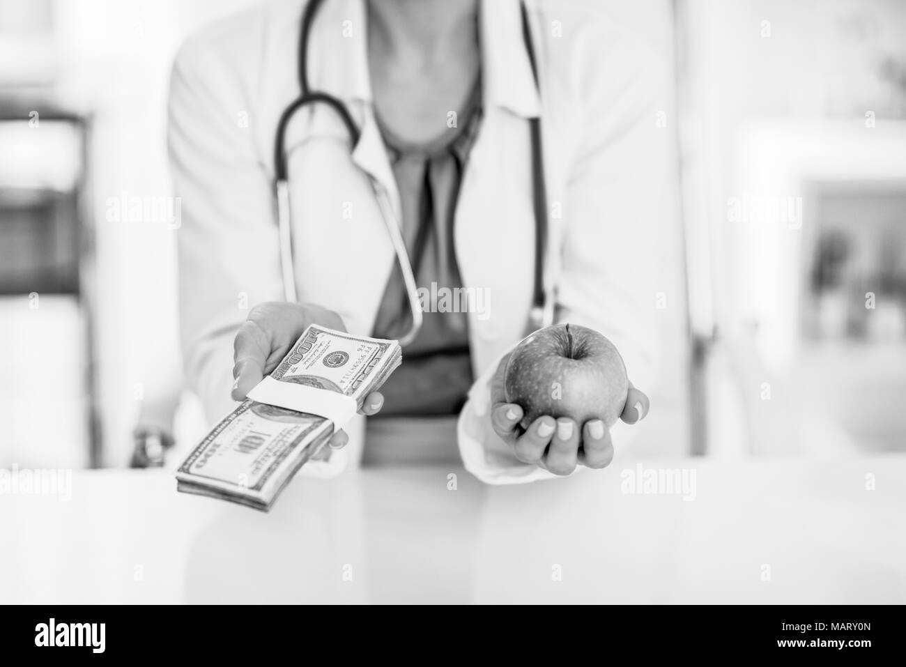Closeup on medical doctor woman holding apple and money pack in hands Stock Photo