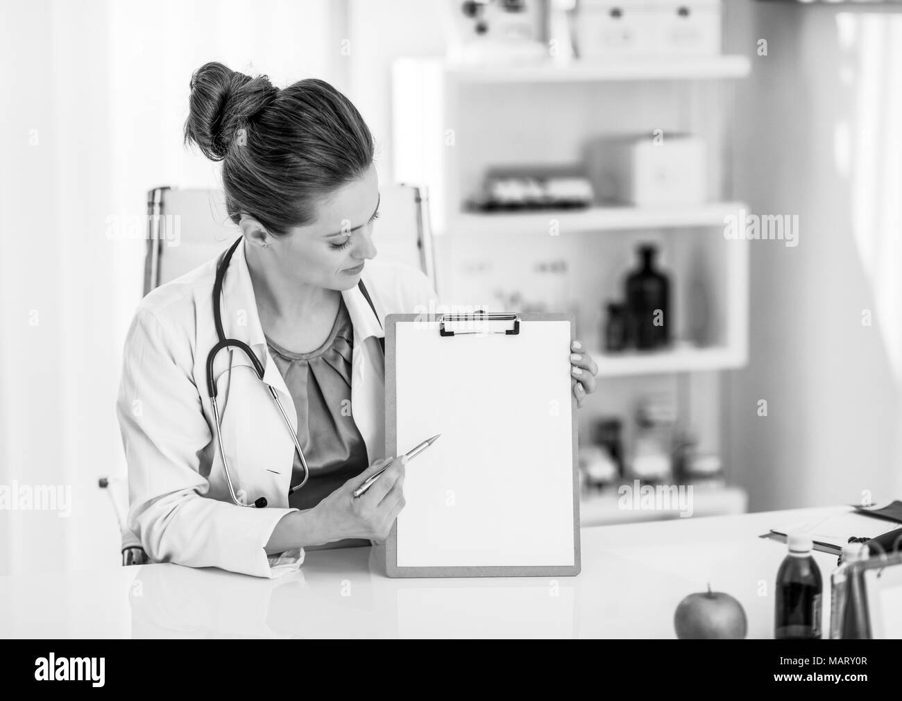 Happy medical doctor woman pointing in clipboard Stock Photo