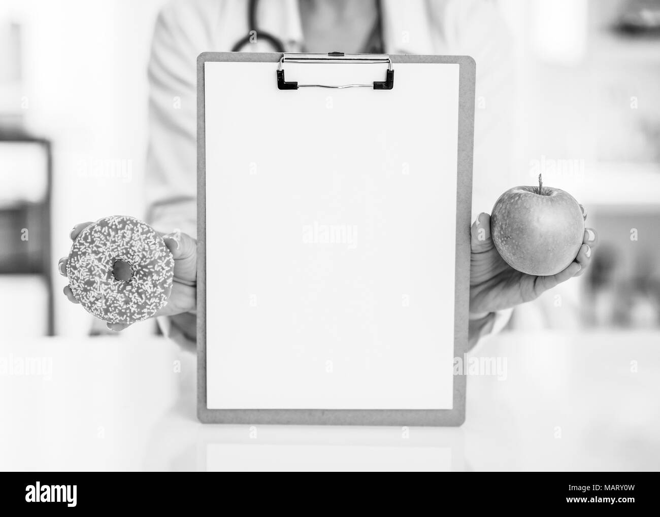 Closeup on medical doctor woman showing blank clipboard apple and donut Stock Photo