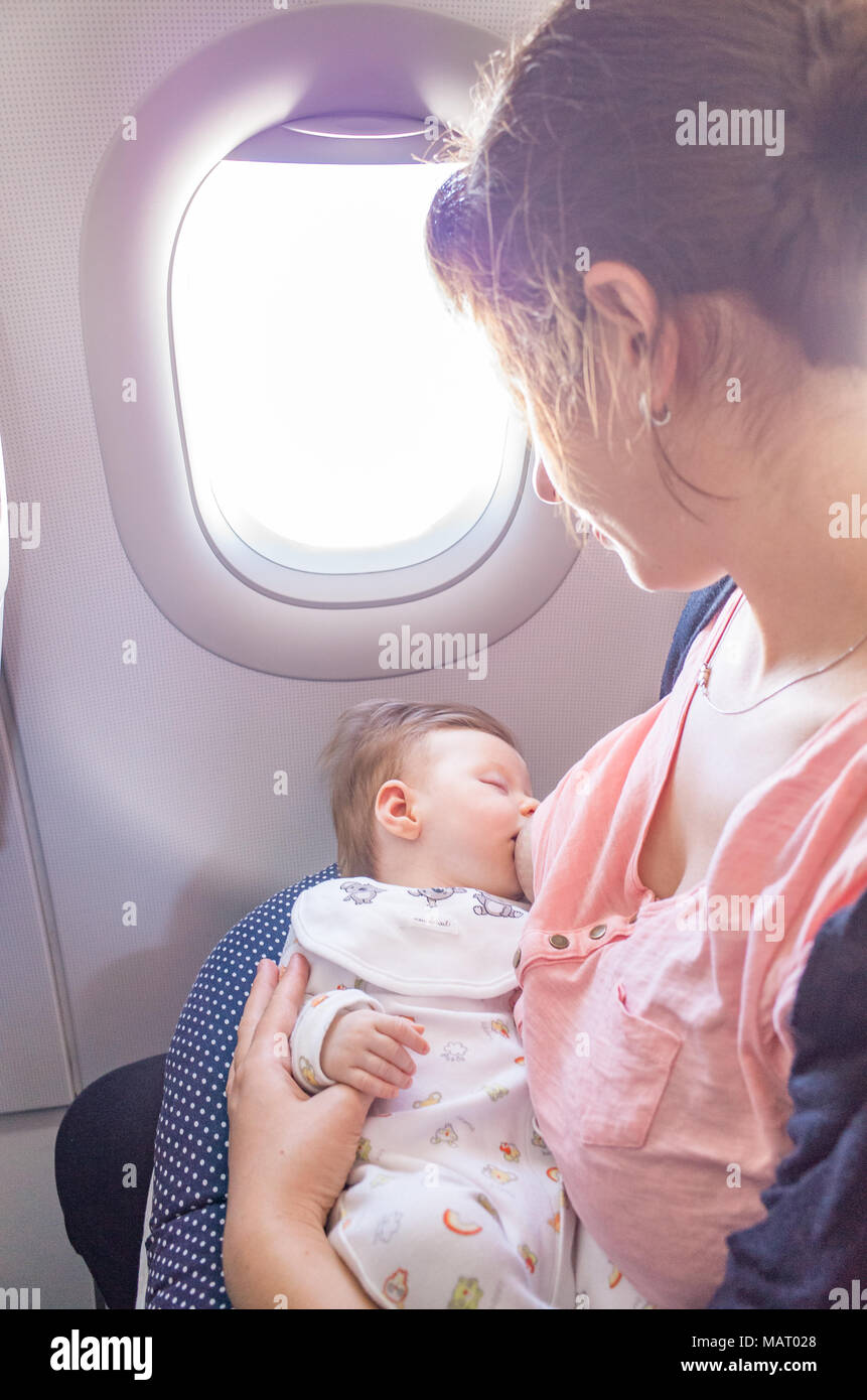 Mother breastfeeding a two month old baby girl on an aeroplane, UK Stock Photo