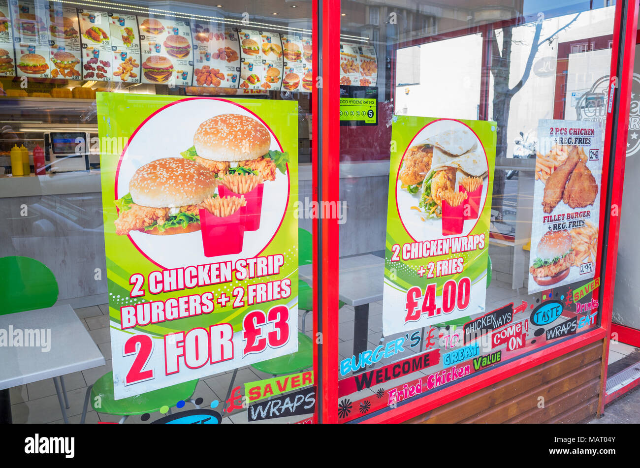 Signs in shop window of a chicken and burger fast food take away, UK, London Stock Photo
