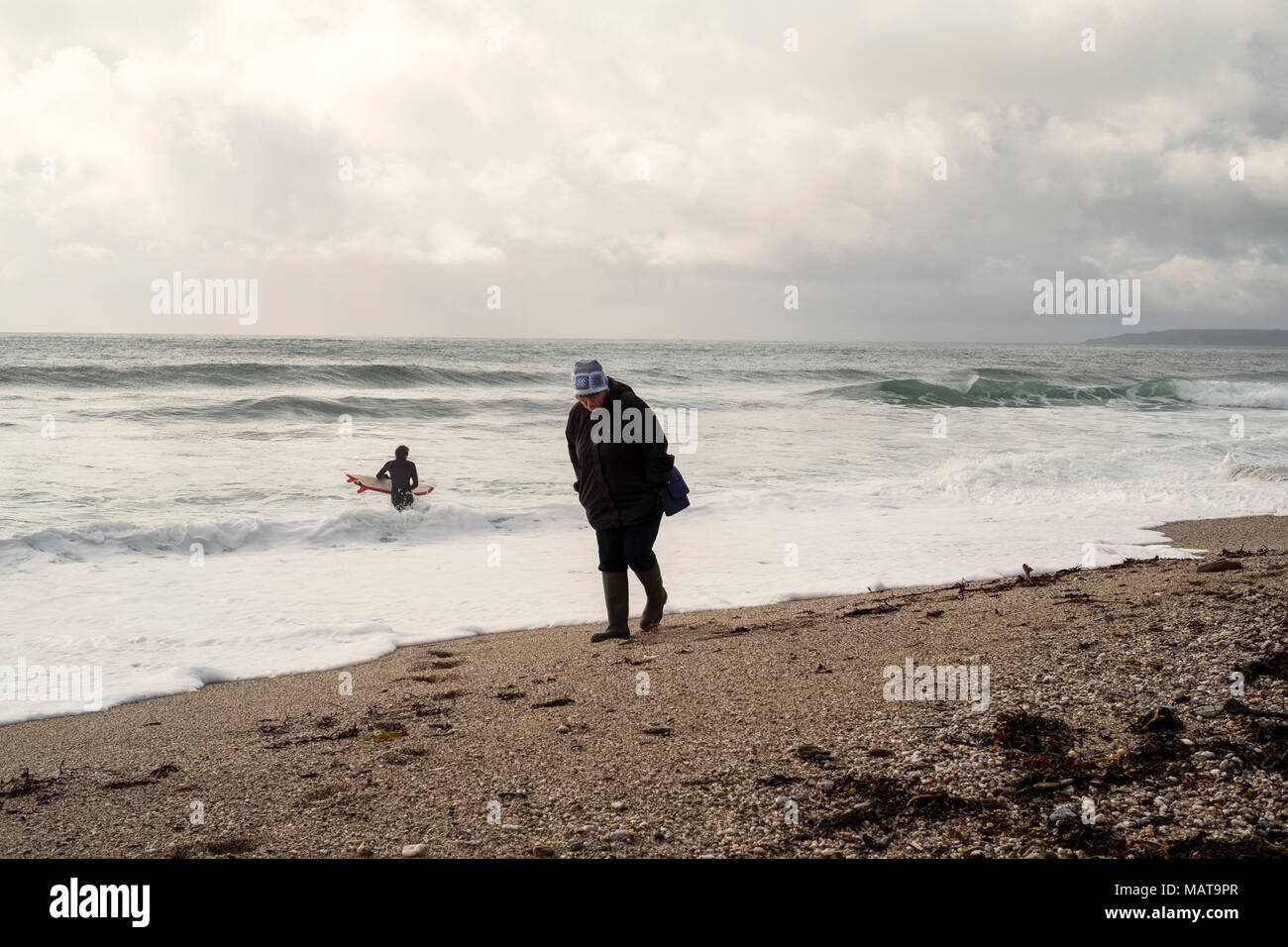 Gyllyngvase beach, Falmouth. 4th Apr, 2018. UK Weather: Surfer braves cold water  at Gyllyngvase beach, Falmouth. A woman walks along Falmouth's Gyllyngvase beach as a surfer enters the water Credit: Mick Buston/Alamy Live News Stock Photo
