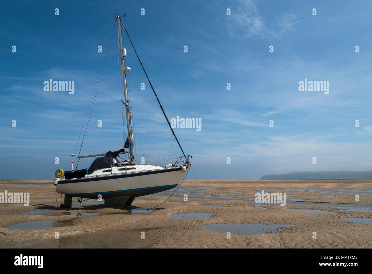 Sailing boat stranded on beach at Red Wharf Bay at low tide Stock Photo