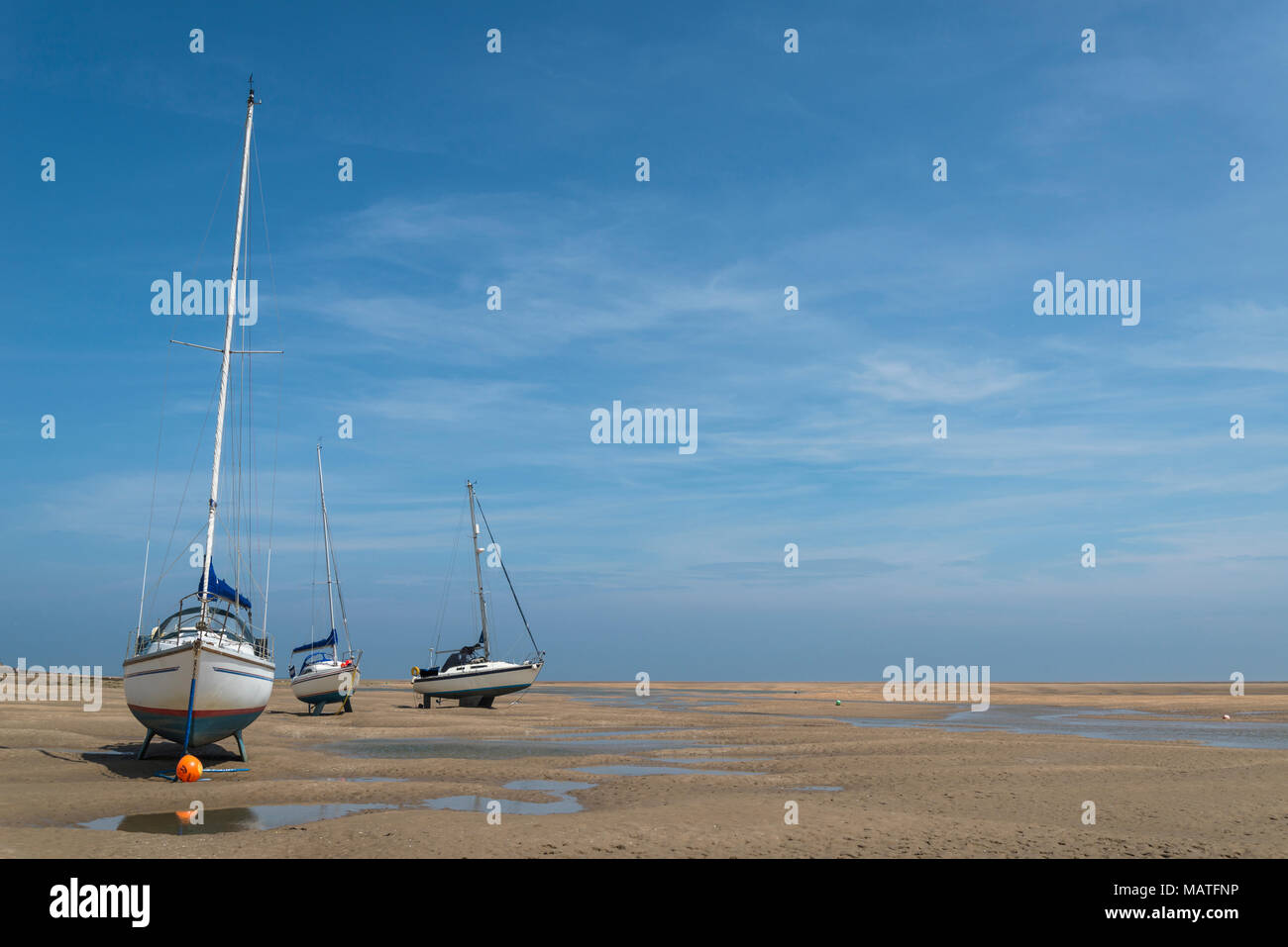 Sailing boats stranded on beach at Red Wharf Bay at low tide Stock Photo