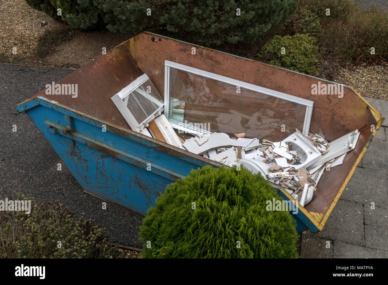 Rubbish skip on the driveway of a house, full of rubble from renovating a bathroom Stock Photo