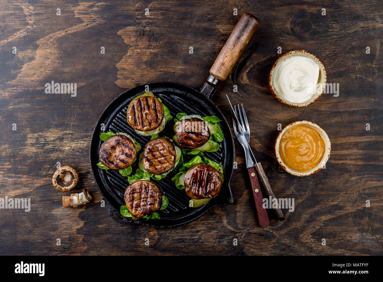 Grilled portobello bun mushroom burgers on cast iron grill pan ob wooden background, top view