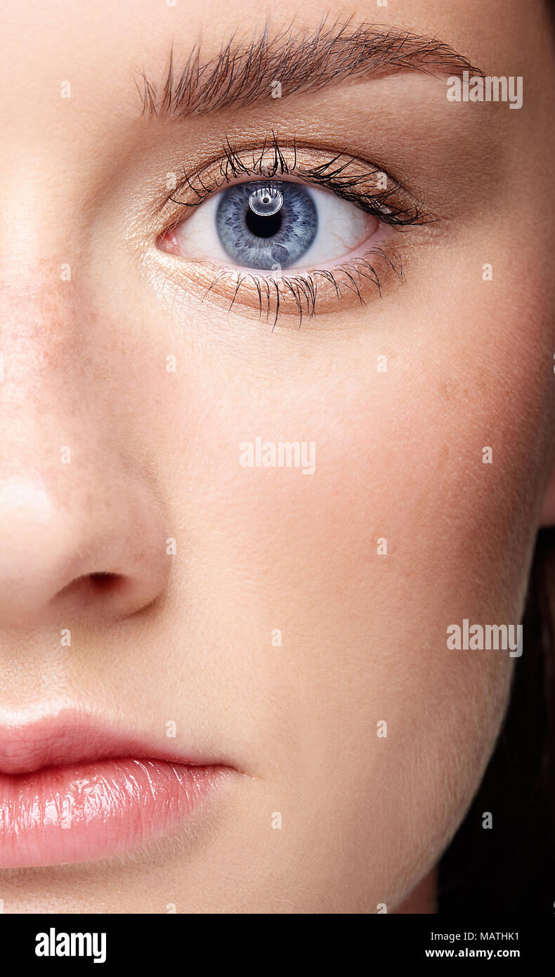 Closeup macro portrait of female face and blue eye. Human woman half-face  with day beauty makeup. Girl with perfect skin and freckles. Stock Photo