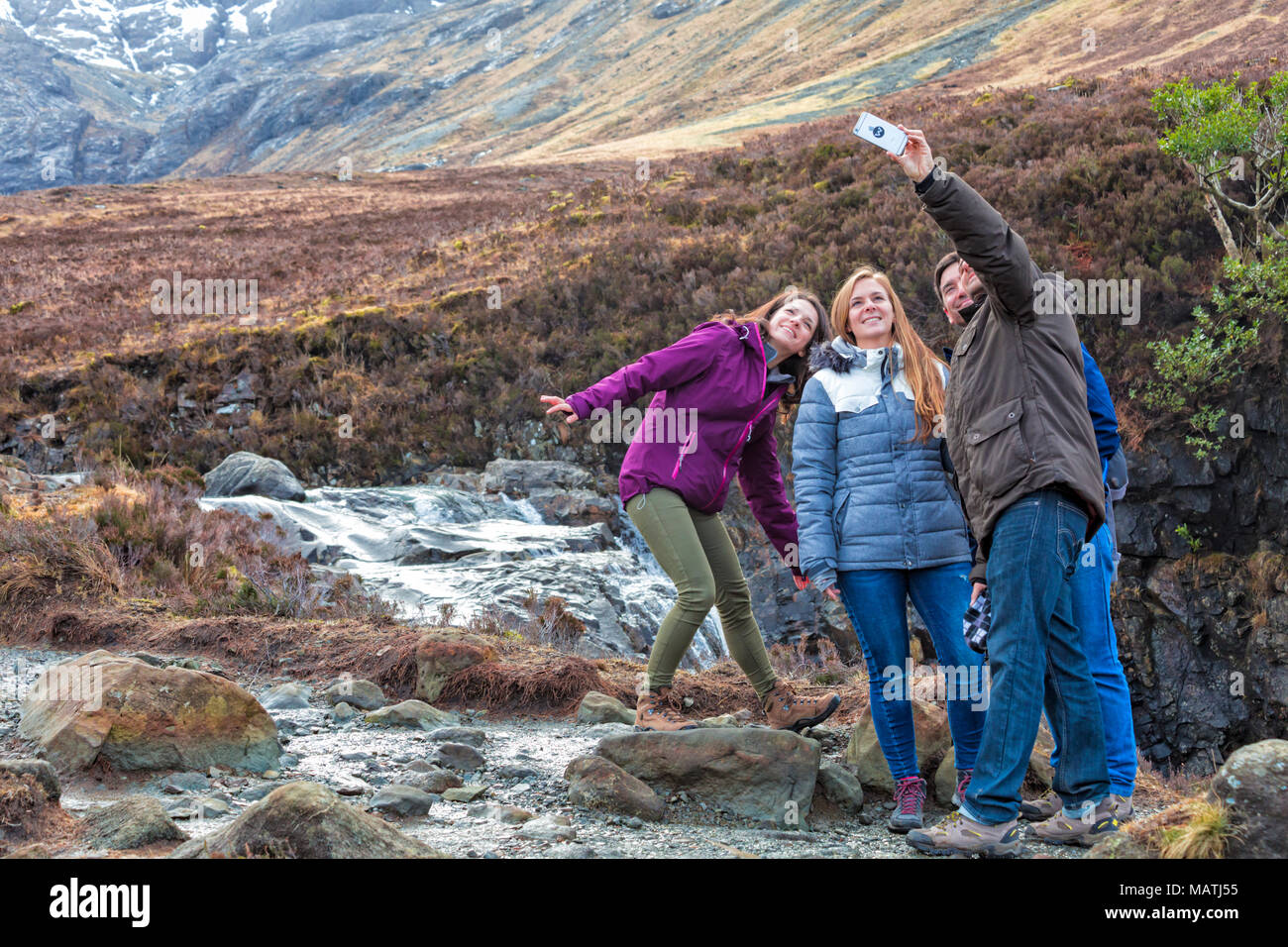 Tourists taking a selfie at Black Cuillin and Fairy Pools, river Brittle, Isle of Skye, Scotland, UK in March Stock Photo