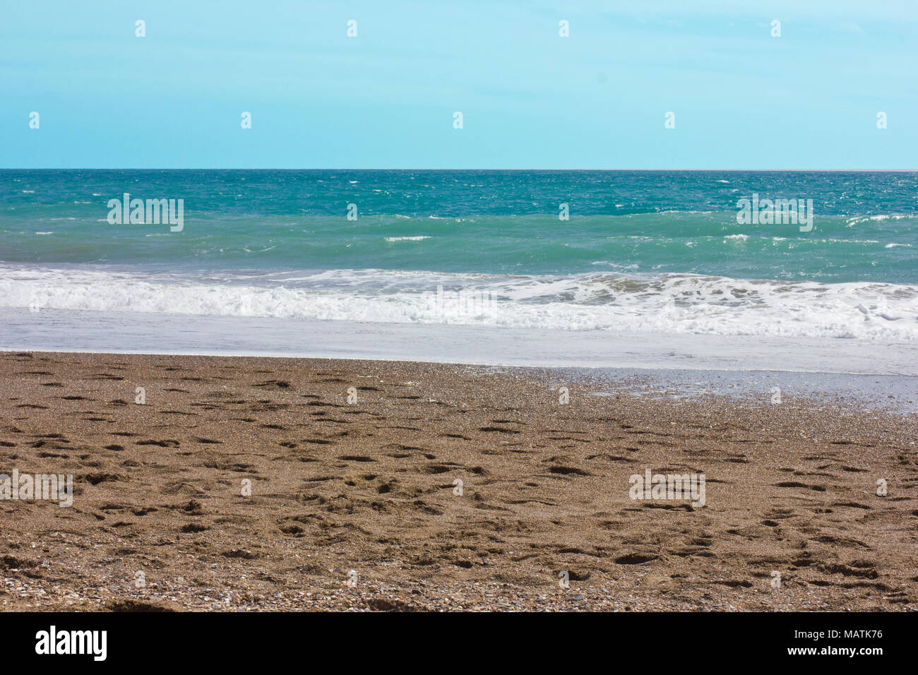 Mediterranean sea and blue sky, white sea foam on the yellow sandy beach. Stock Photo