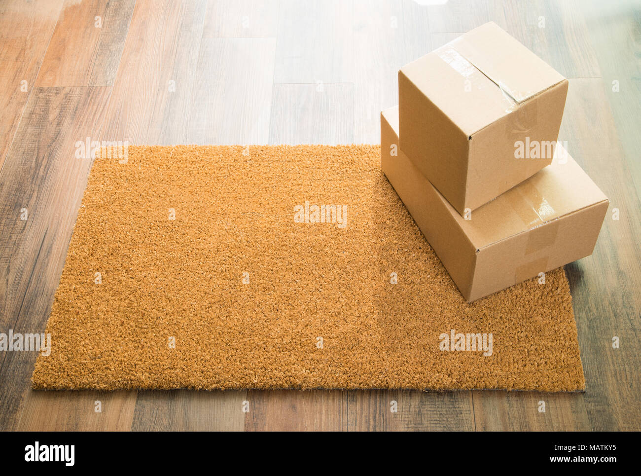 Blank Welcome Mat On Wood Floor With Shipment of Boxes. Stock Photo