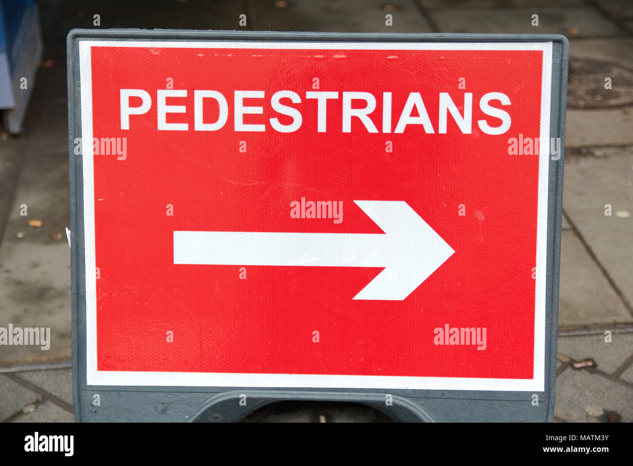 Red and white rectangular road safety sign pedestrians this way, arrow guiding pedestrians safely Stock Photo