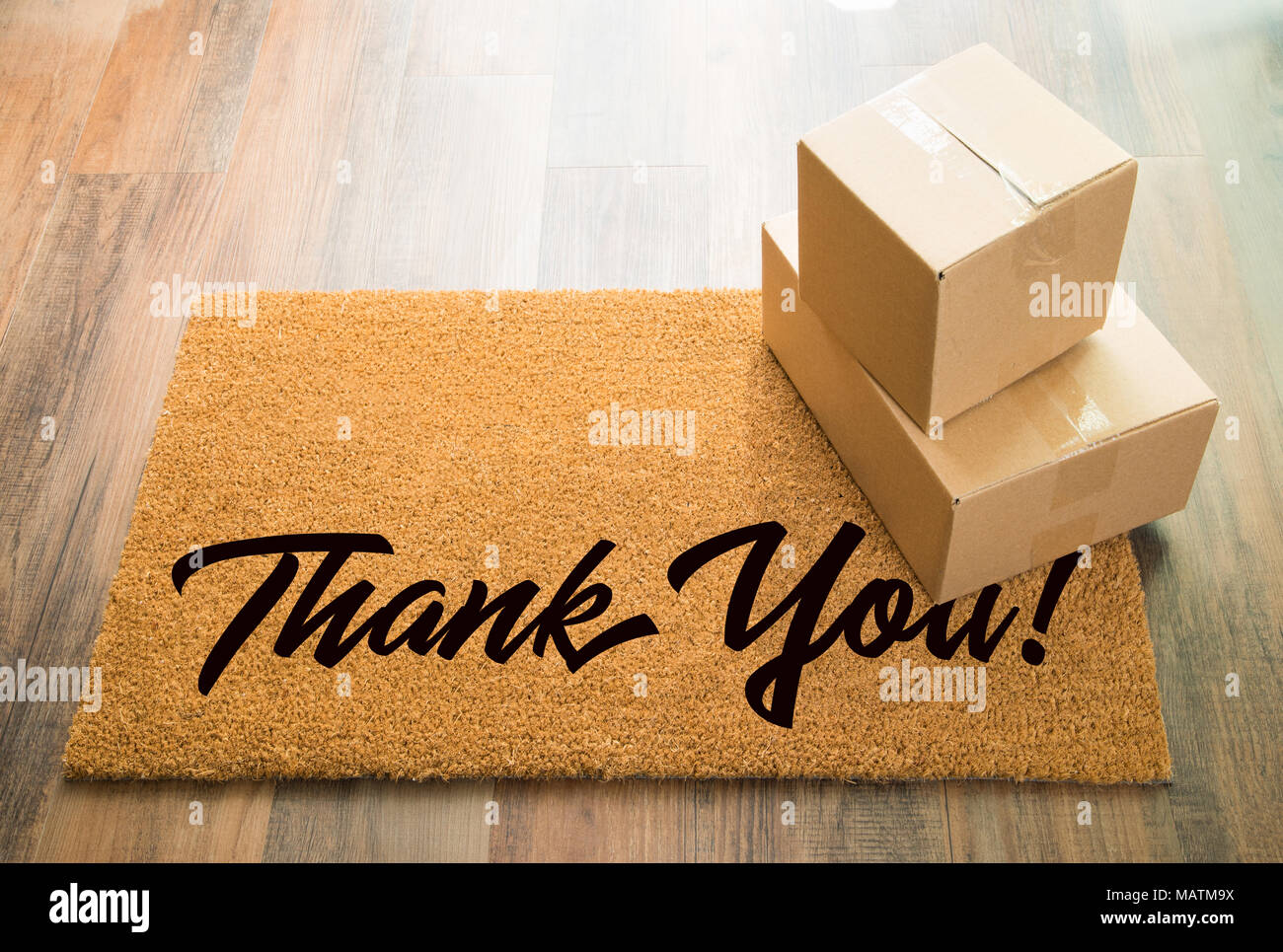 Thank You Welcome Mat On Wood Floor With Shipment of Boxes. Stock Photo
