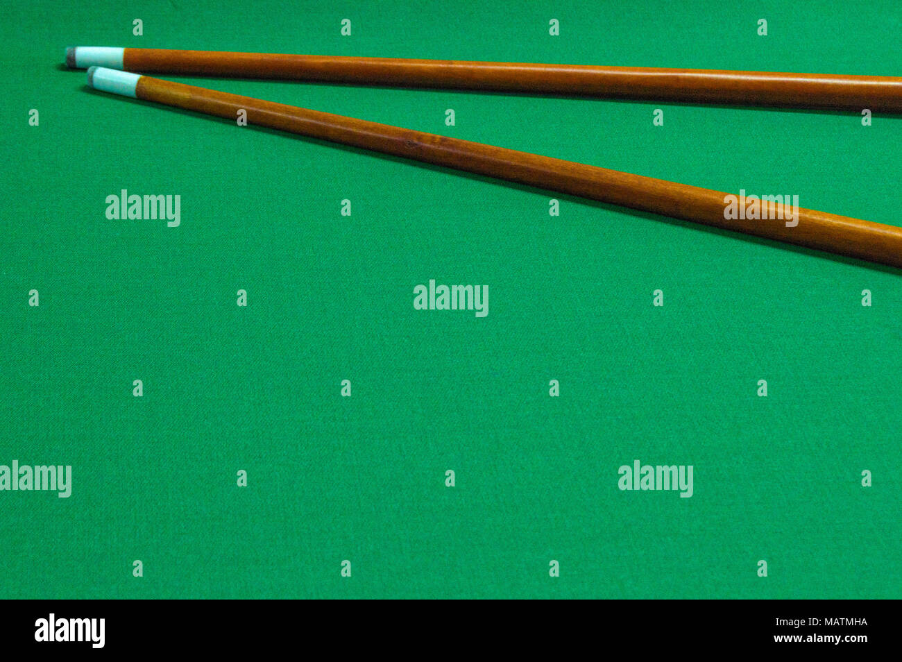 two pool cues on the green background of the pool table Stock Photo