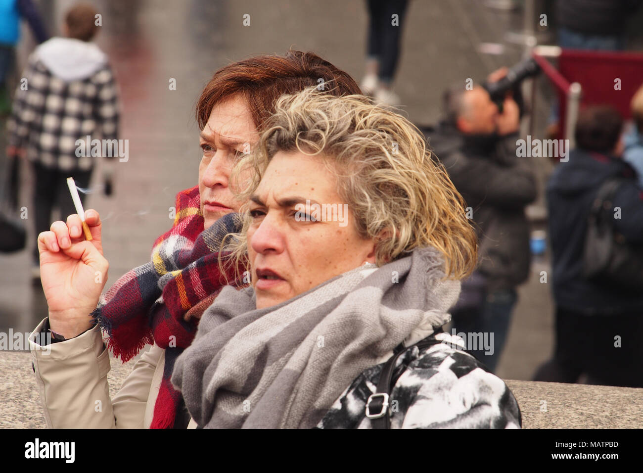 Two women smoking cigarettes sightseeing in London on a cold winter day Stock Photo