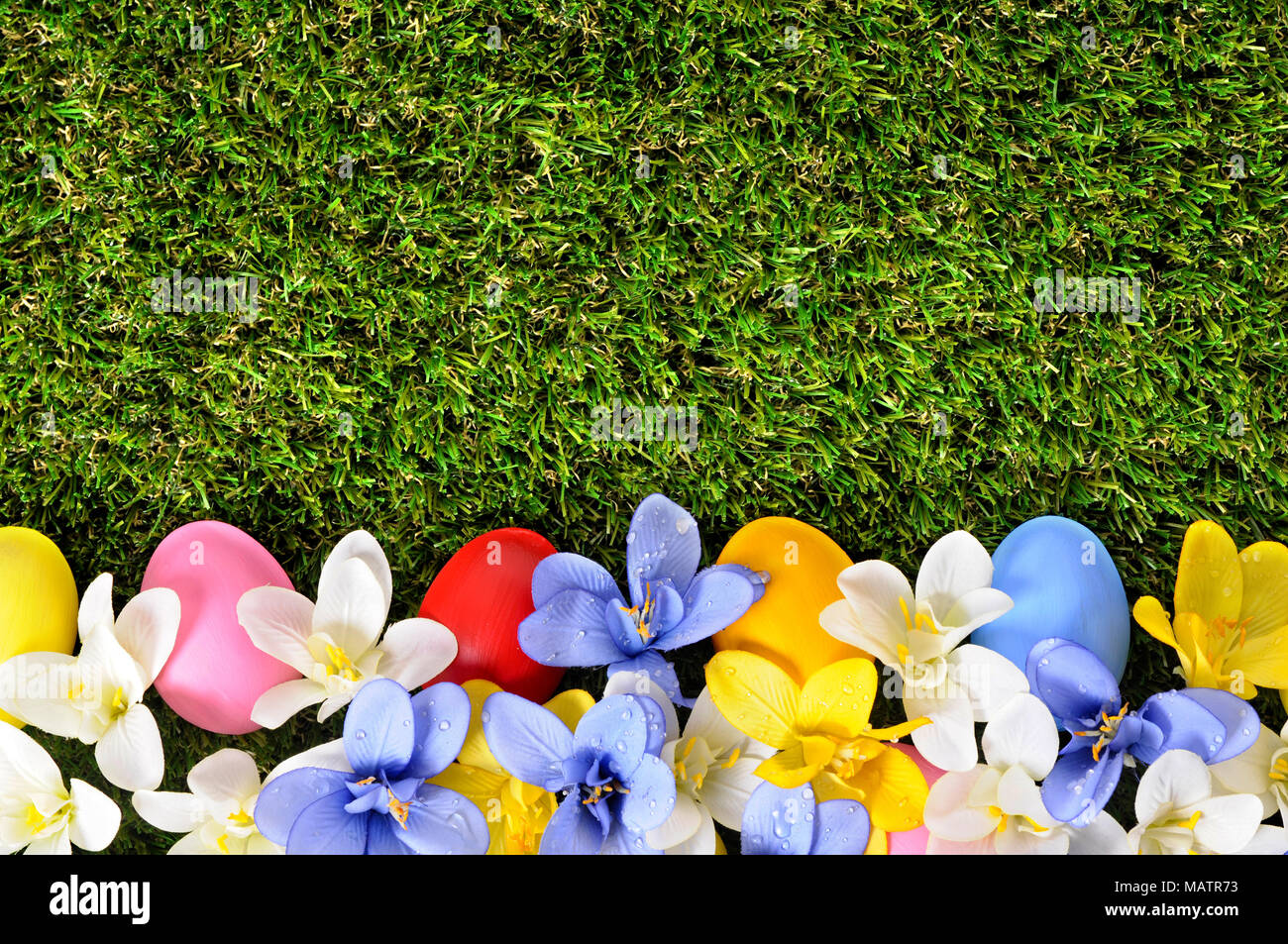 Easter background with hand painted eggs hidden in flowers with copyspace. Stock Photo