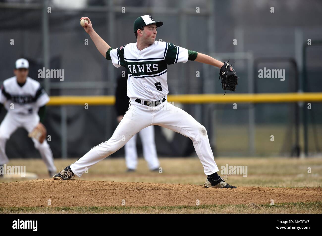Pitcher delivering a pitch to an opposing hitter during a high school